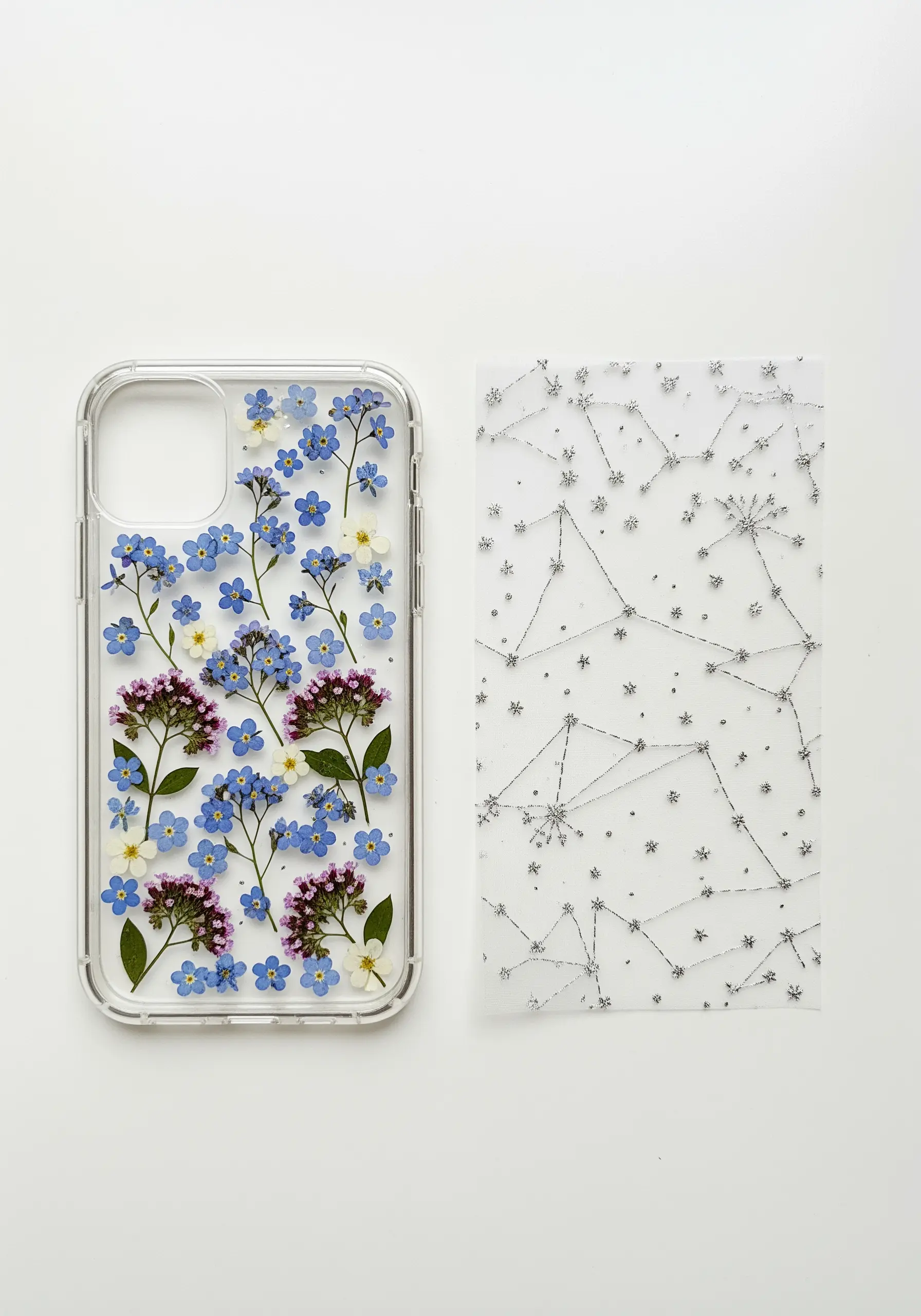 A clear phone case with pressed flowers and a separate embroidered insert with a silver constellation.