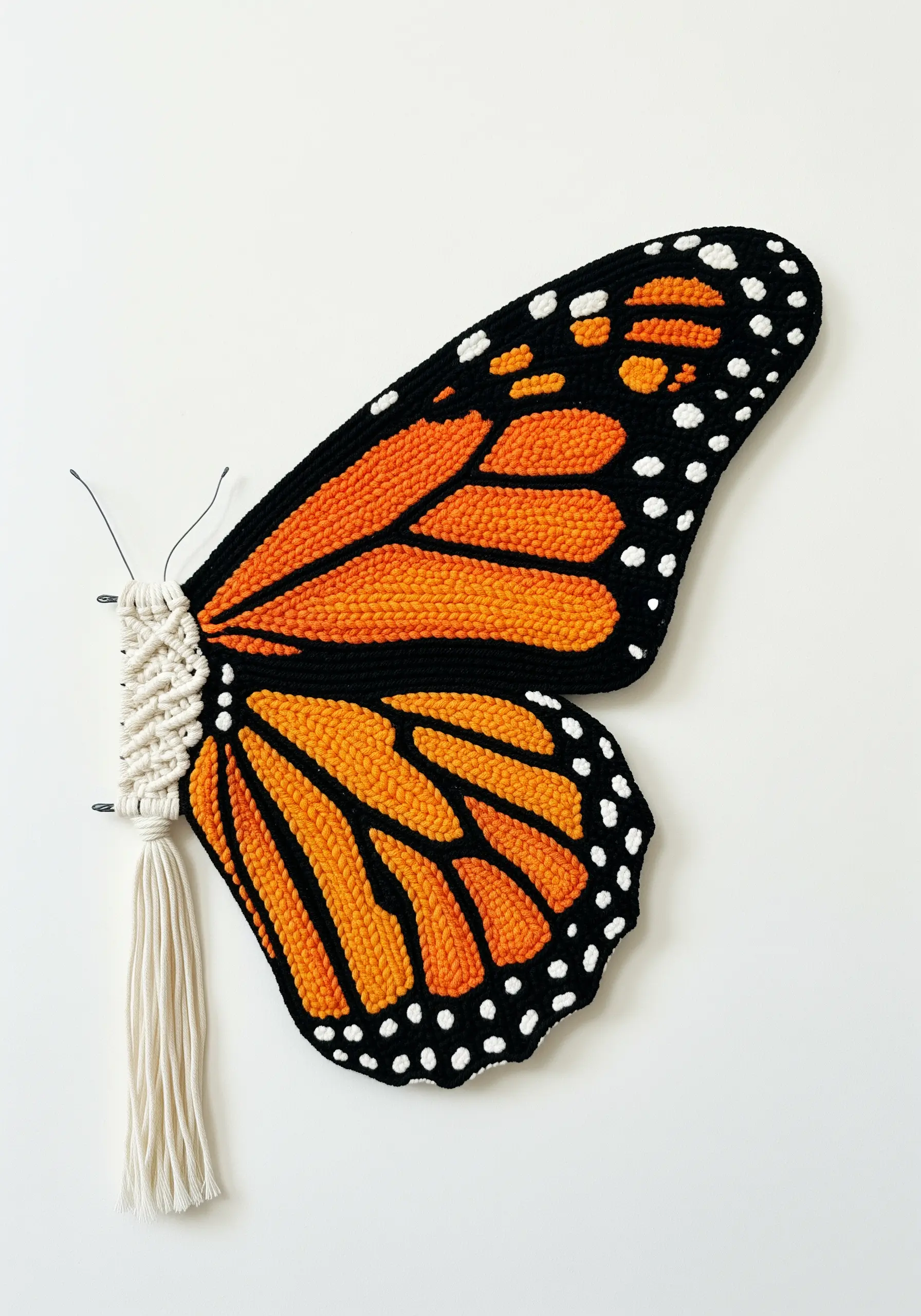A monarch butterfly wing combining a macrame body with a punch needle wing.