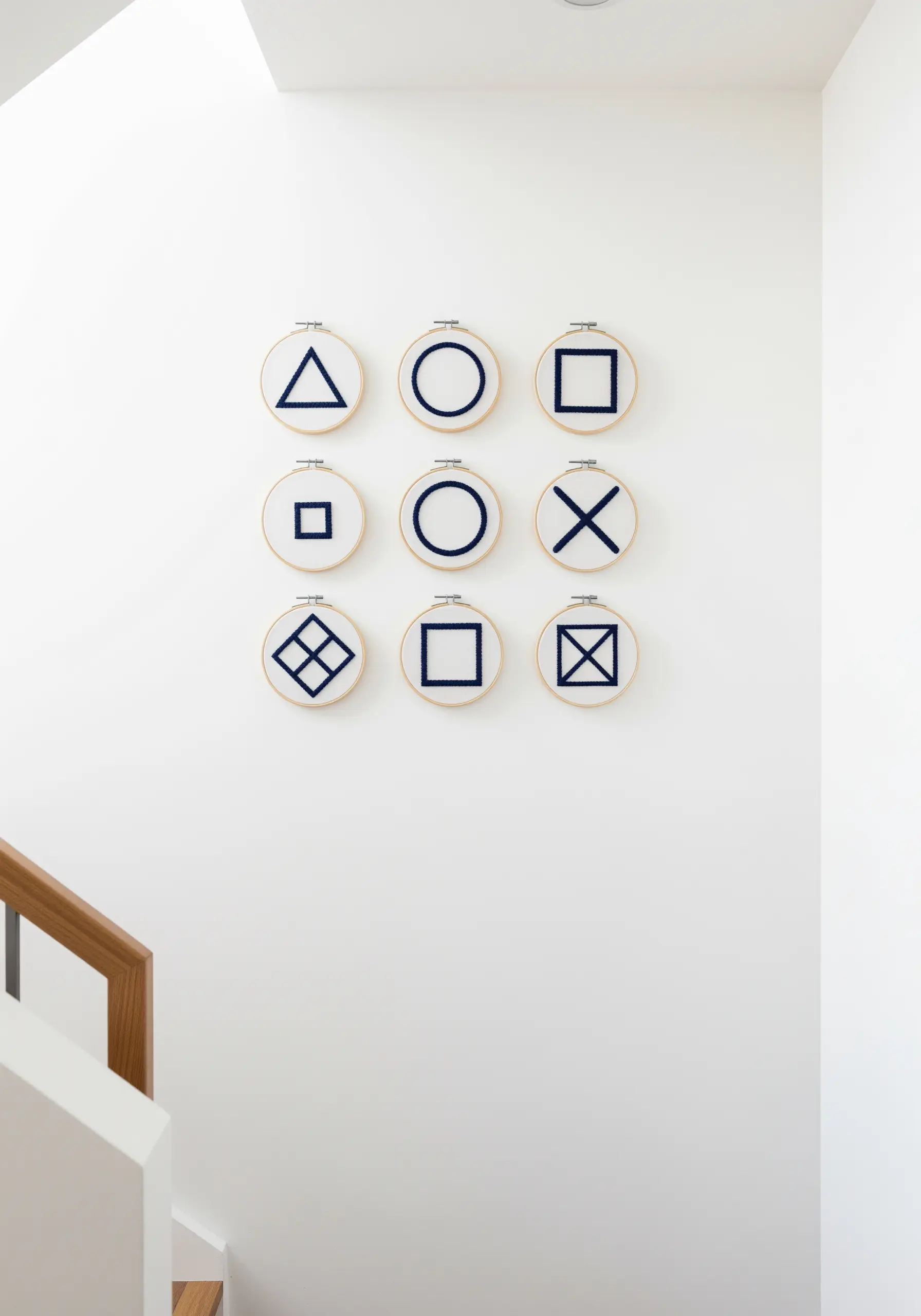 A nine-hoop grid displaying simple geometric symbols embroidered in dark blue.