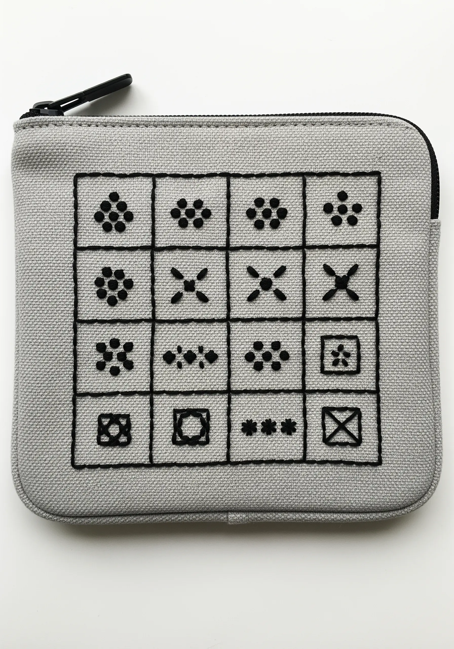 A grid of small, black embroidered symbols on a gray zippered pouch.