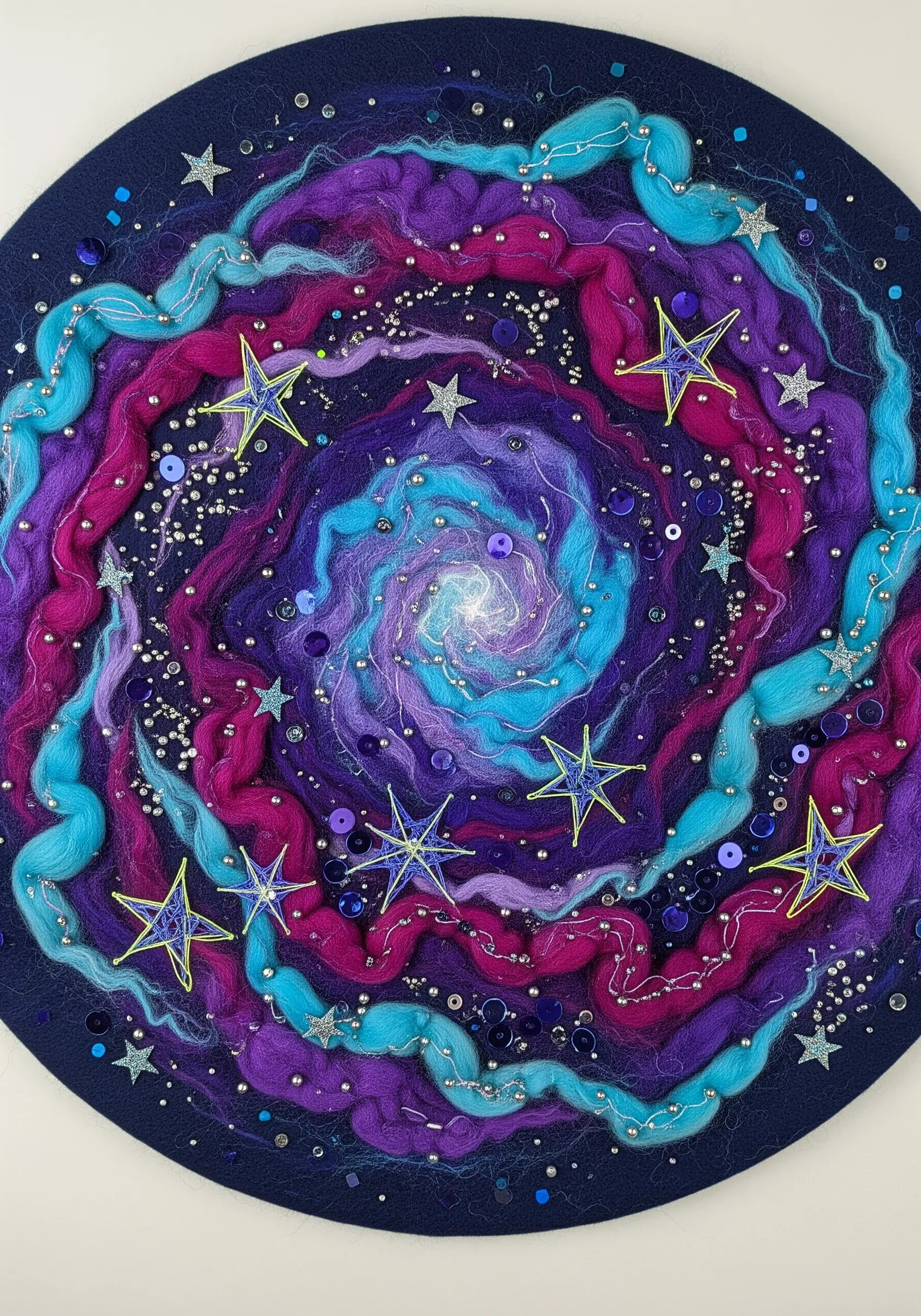A needle-felted galaxy in purples and blues, embellished with sequins and embroidered stars.