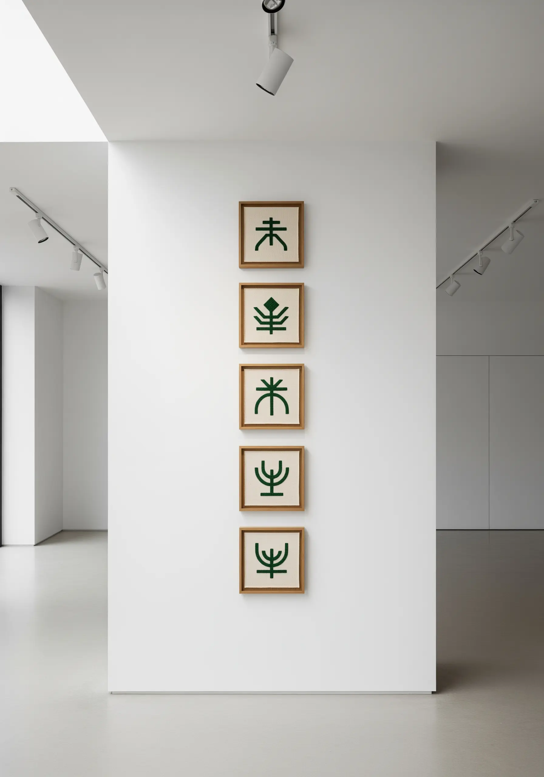 Five framed embroideries with abstract dark green symbols displayed vertically.