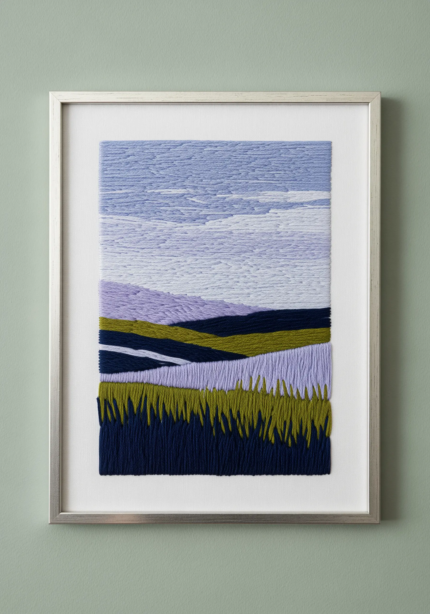 Framed abstract landscape embroidery with blocks of color in purple, green, and blue.