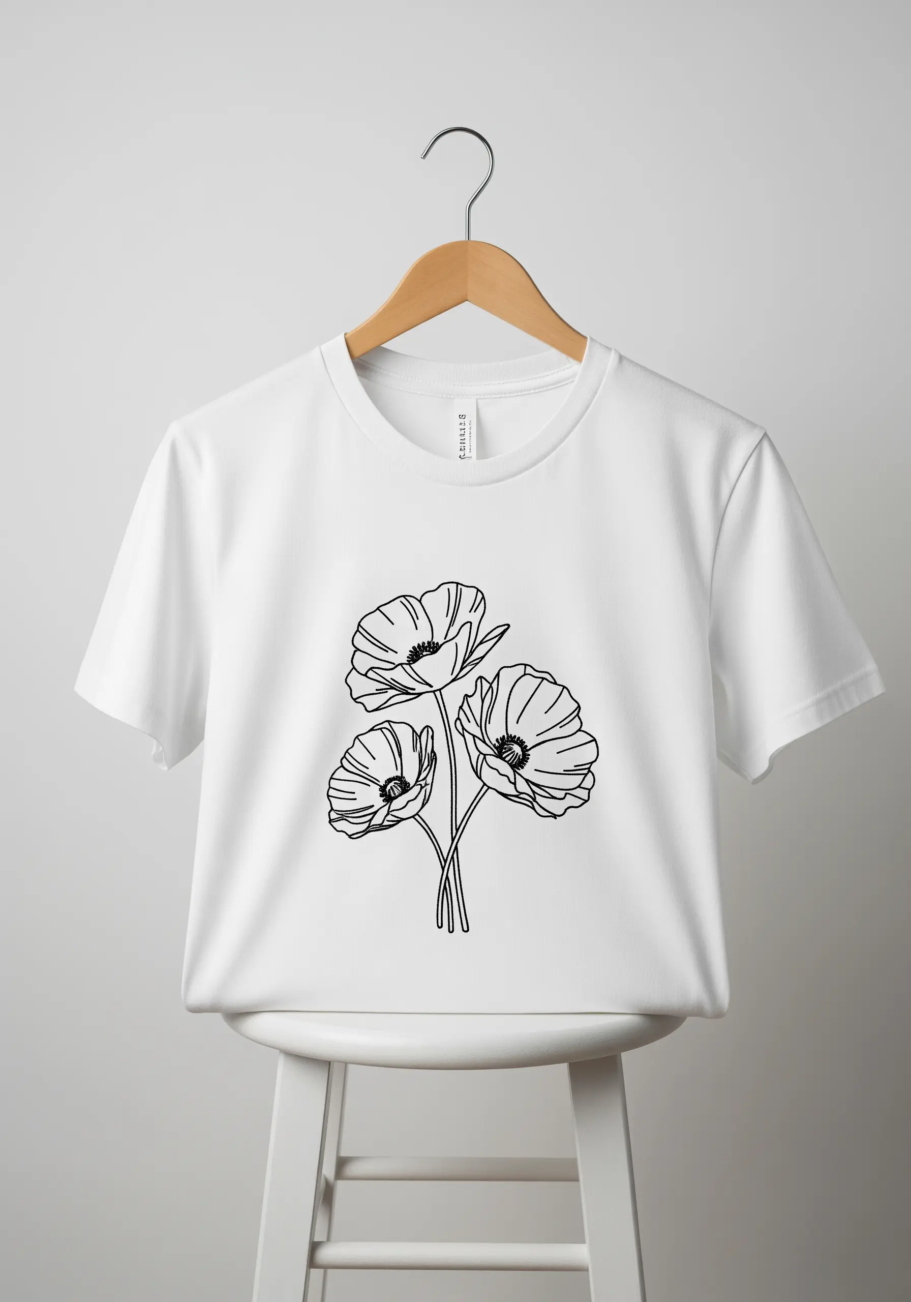 Black line-art embroidery of three poppy flowers on a white t-shirt.