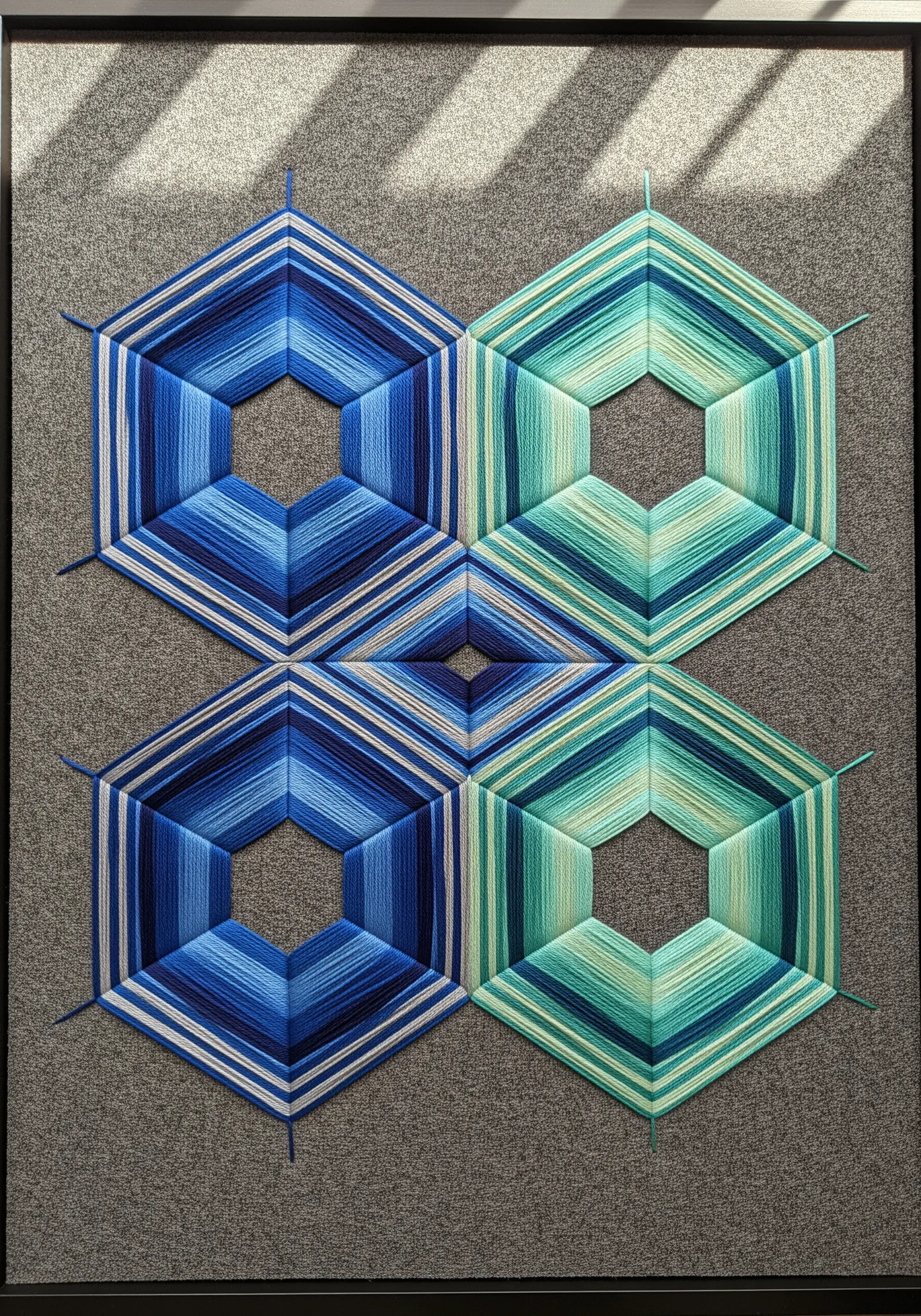 Geometric string art using blue and green variegated thread for a gradient effect.