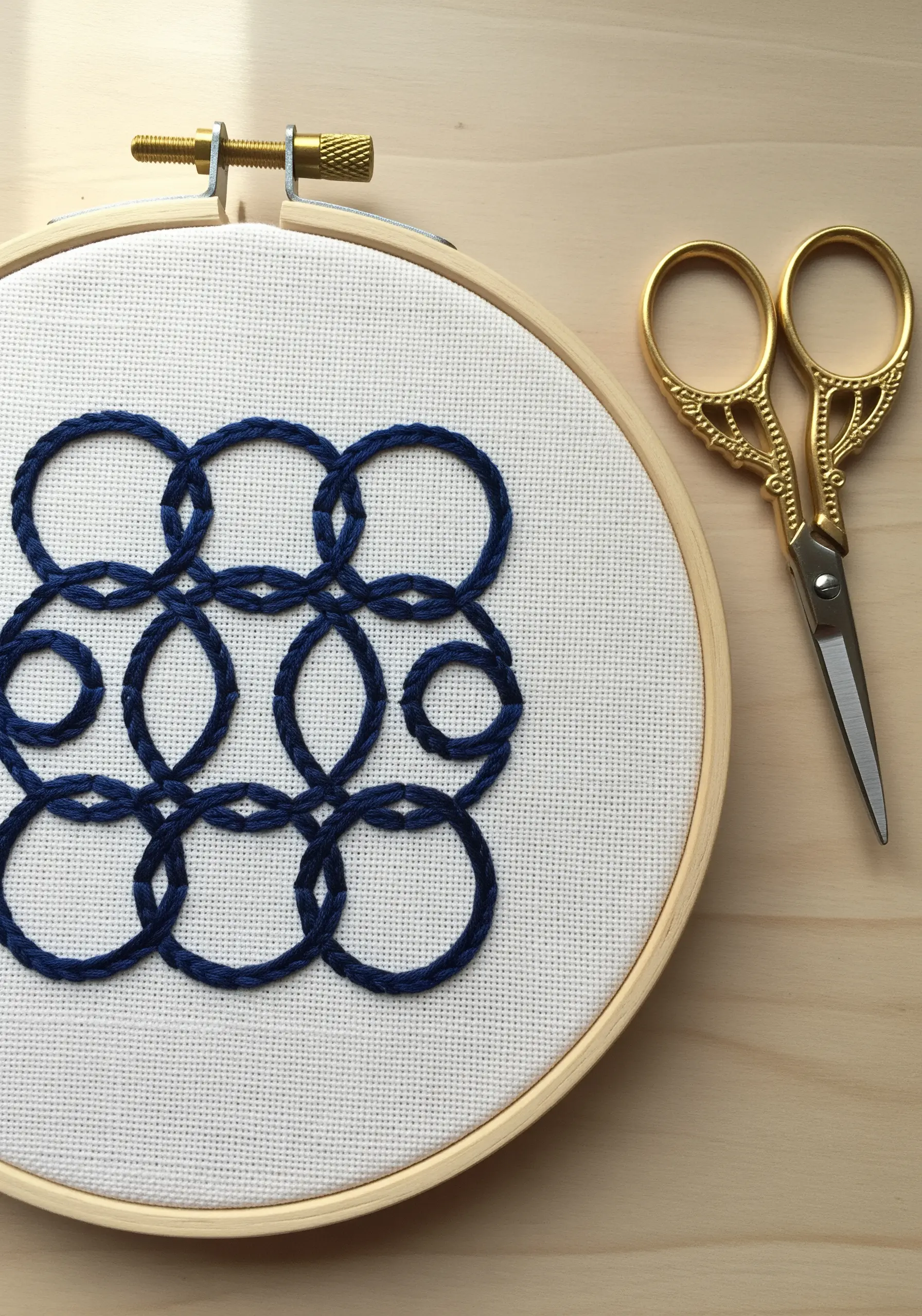 An intricate geometric pattern of interlocking circles embroidered in navy blue thread.