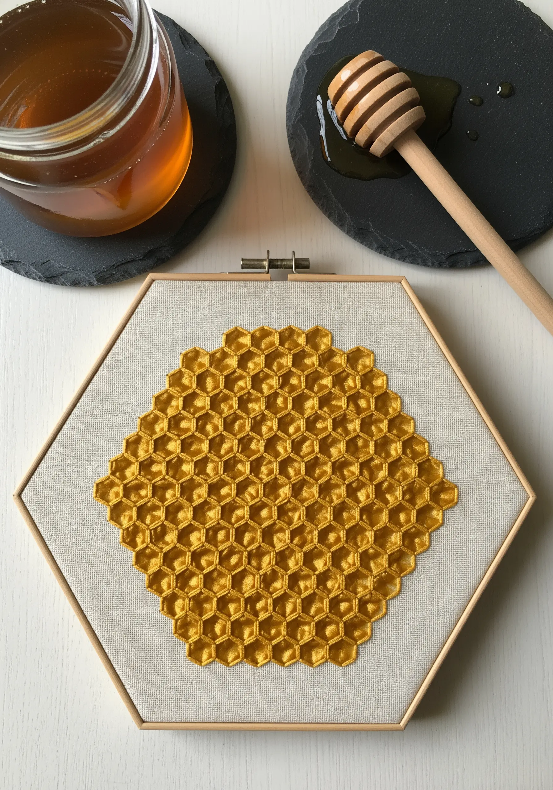 A precise geometric honeycomb pattern embroidered in golden yellow thread within a hexagonal hoop.
