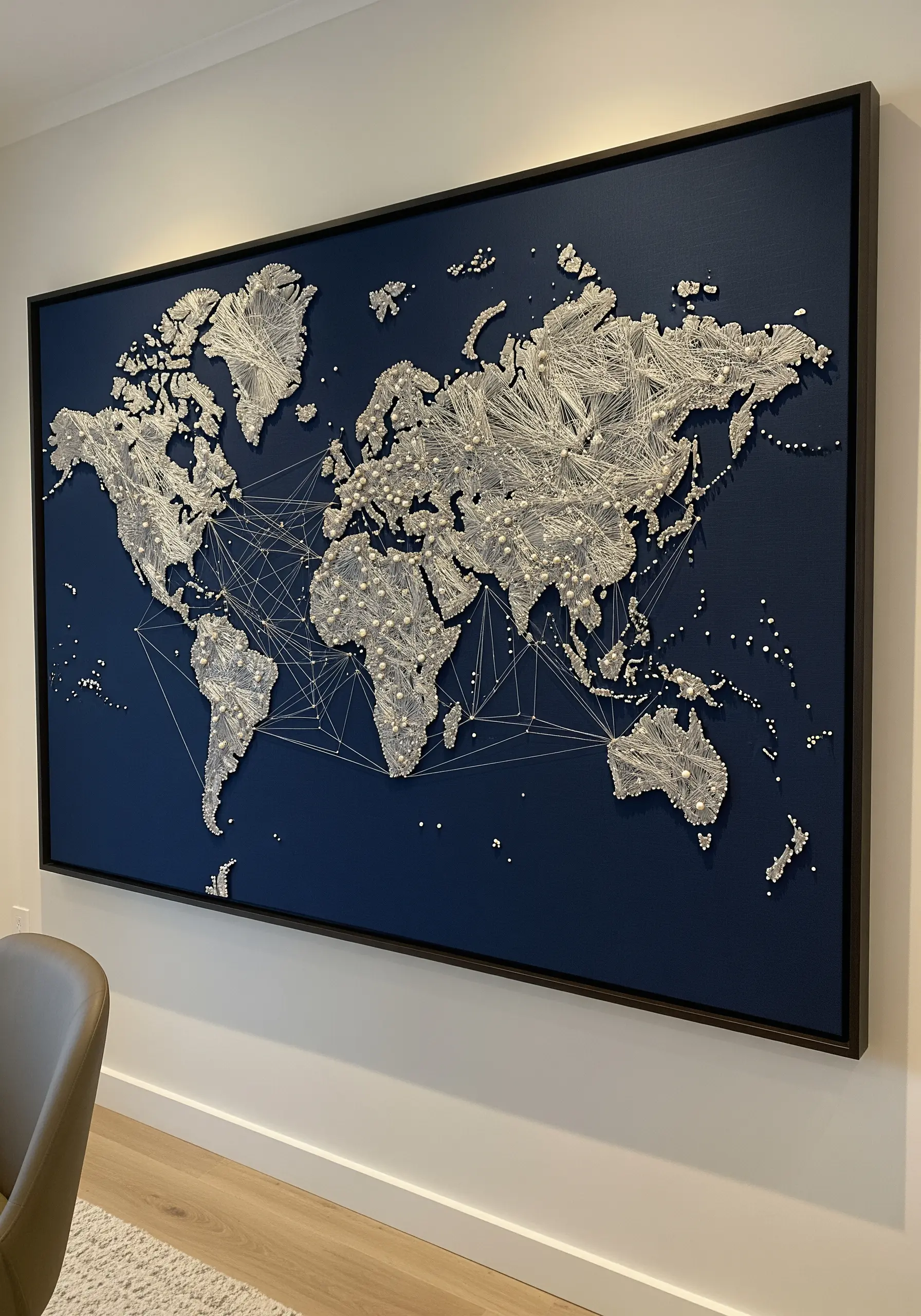 Large-scale string art world map with silver thread on a dark blue canvas, framed in black.