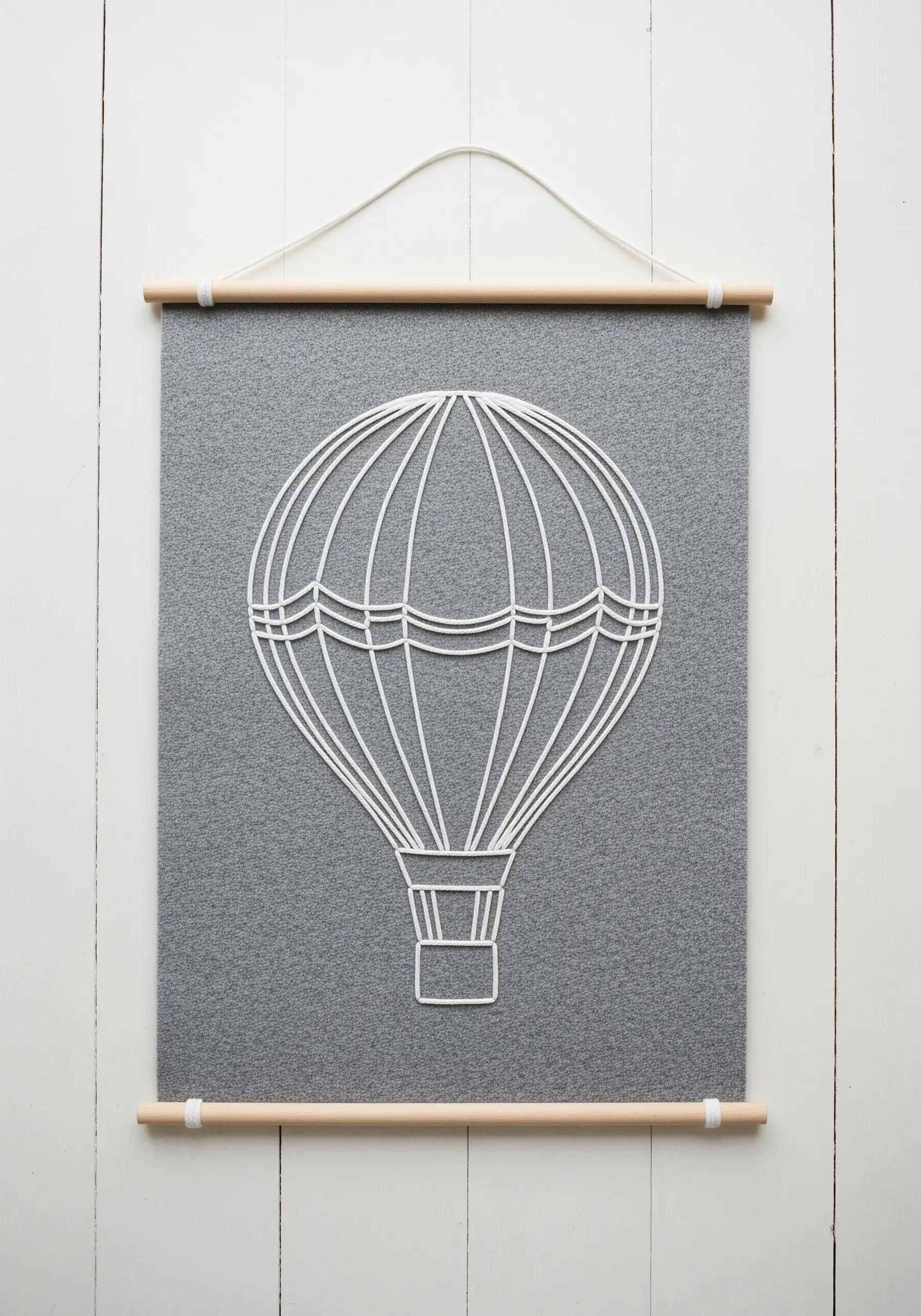 A white cord couched onto a grey felt banner to form a hot air balloon outline.