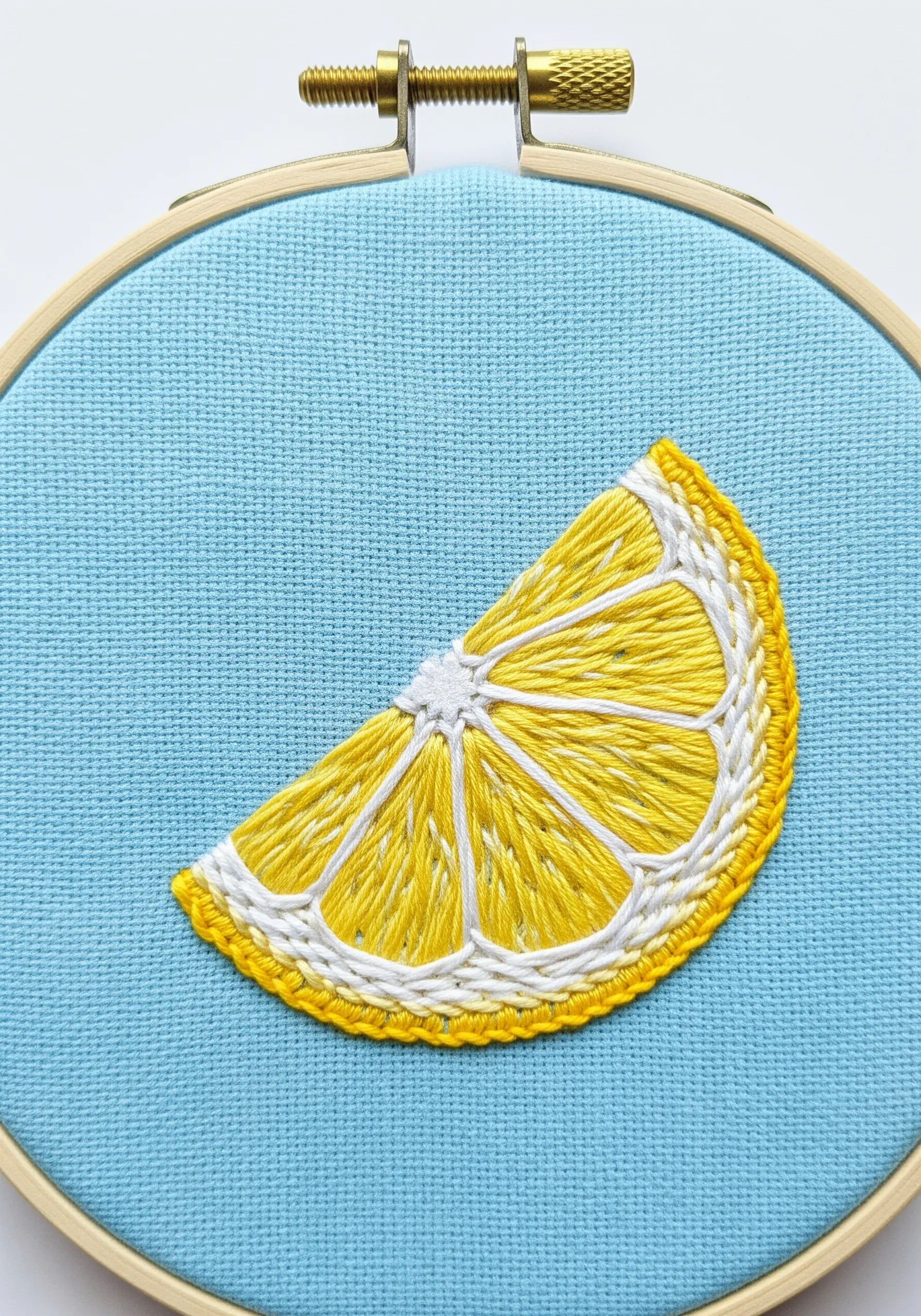 A bright slice of lemon embroidered on blue fabric with defined white segment lines.