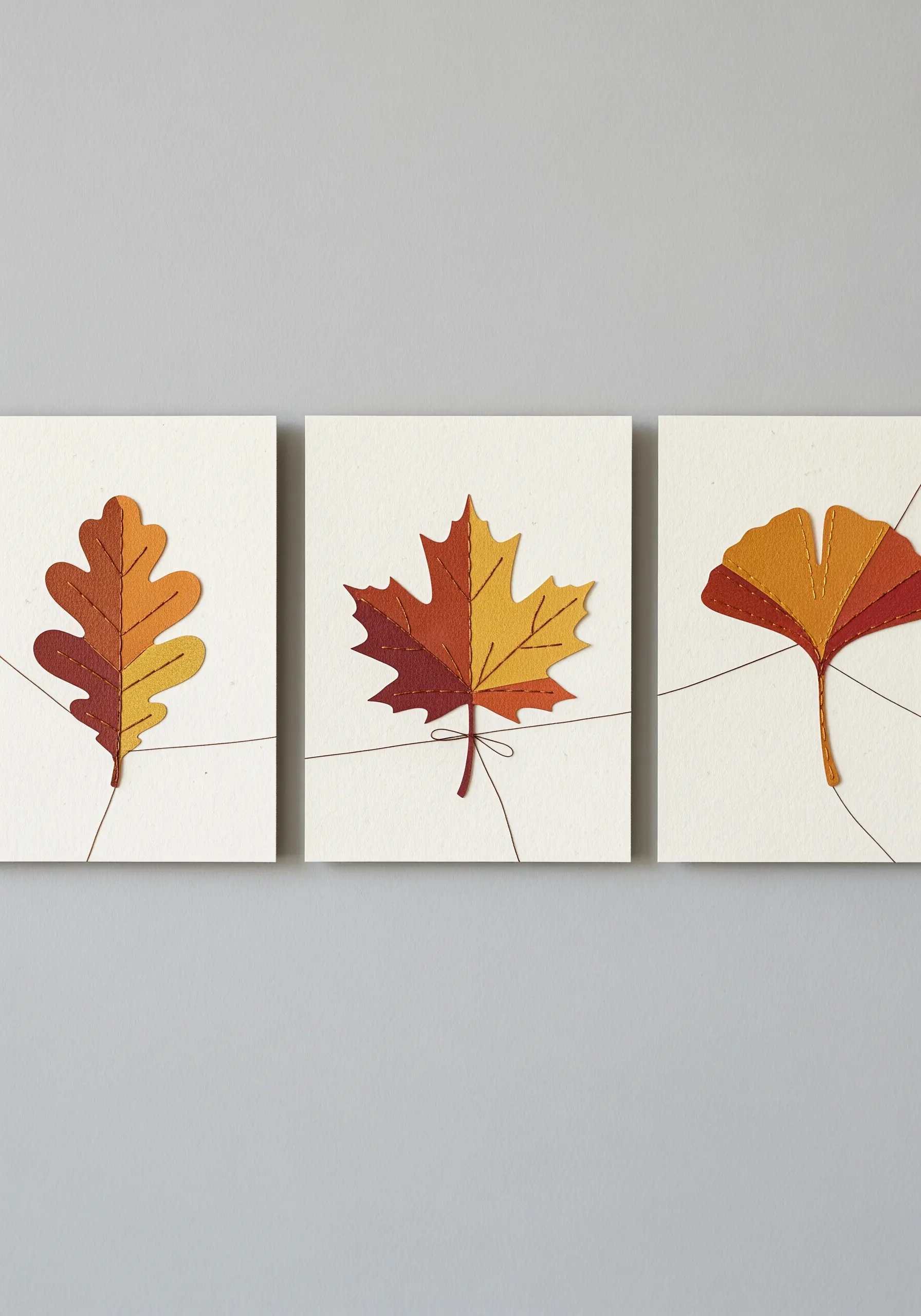 Three square cards with stitched paper autumn leaves, connected by a single brown thread.