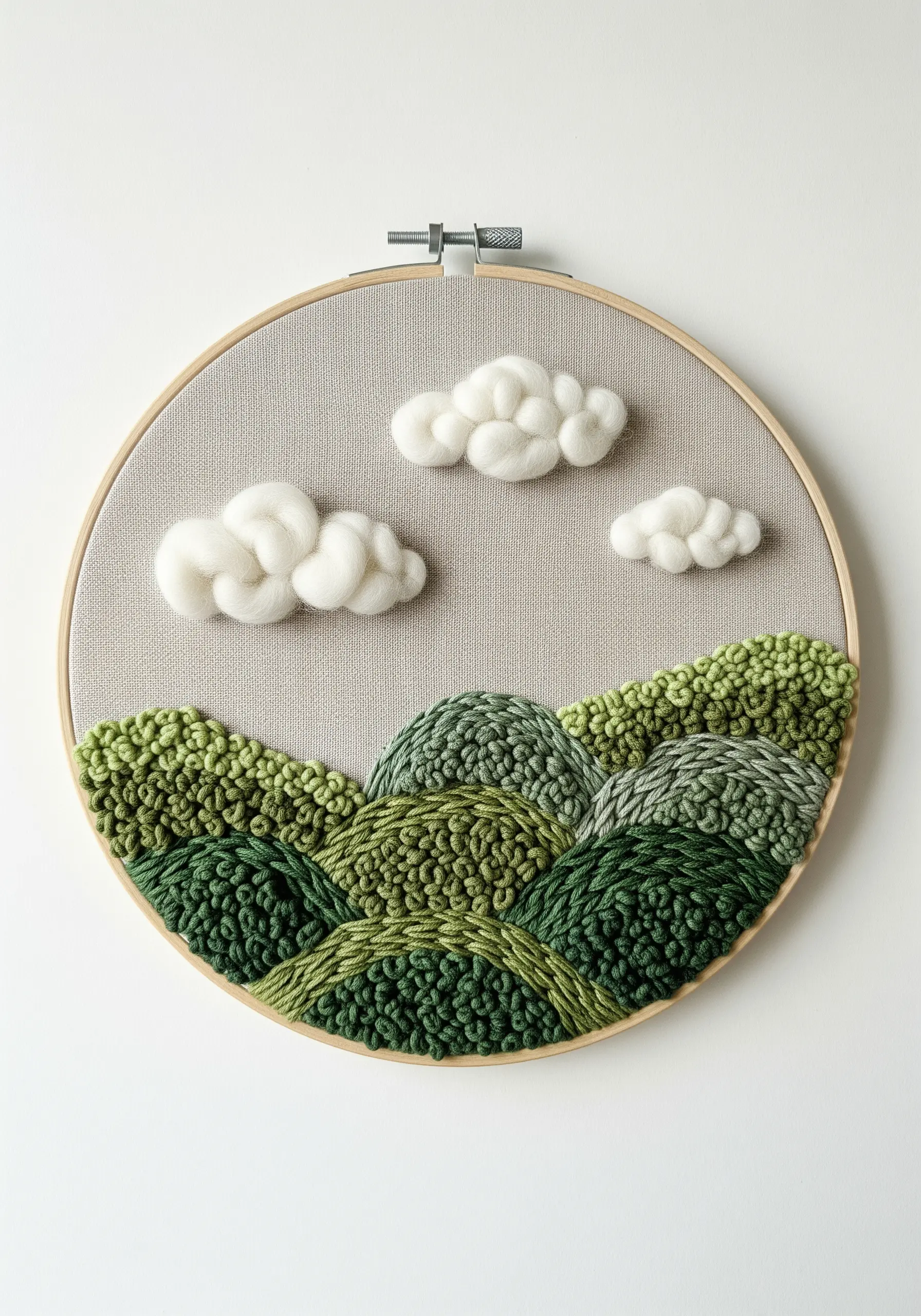An embroidery hoop with a landscape of green, punch-needled hills and fluffy, 3D felted clouds.