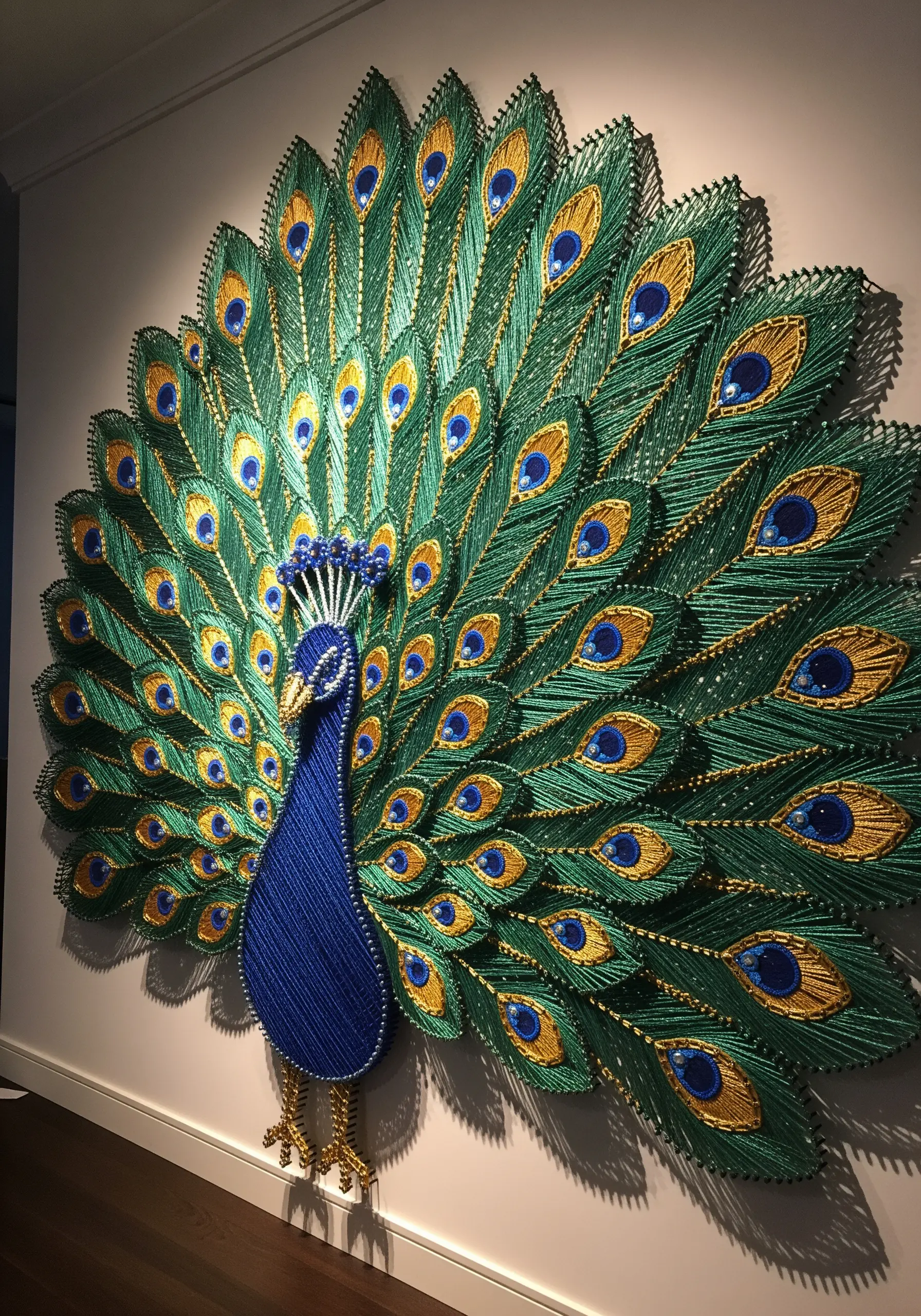 Elaborate string art peacock with green, blue, and gold feathers and decorative embellishments
