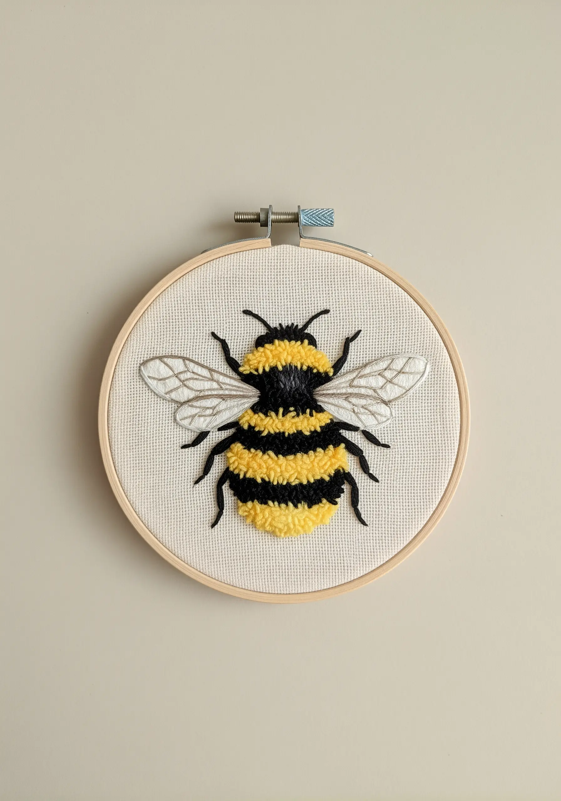 Embroidered bumblebee with a fluffy body made from yellow and black turkey work stitch.