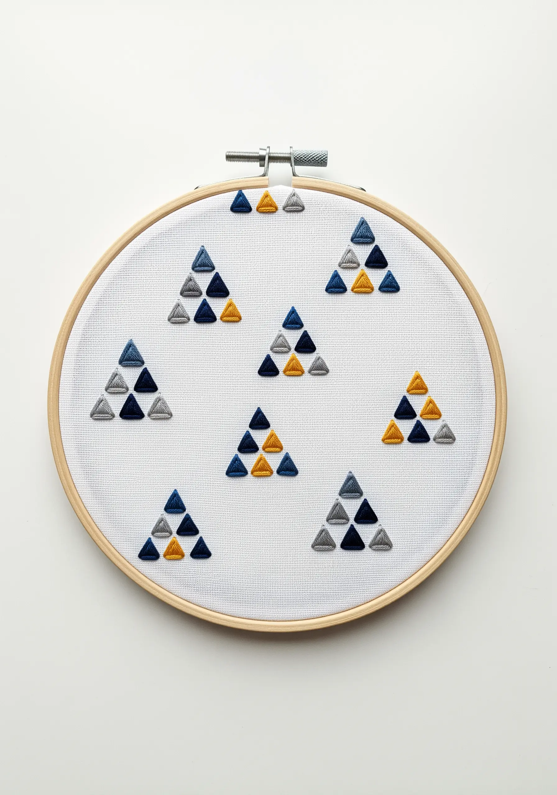A geometric pattern of small triangles filled with satin stitch in different directions.