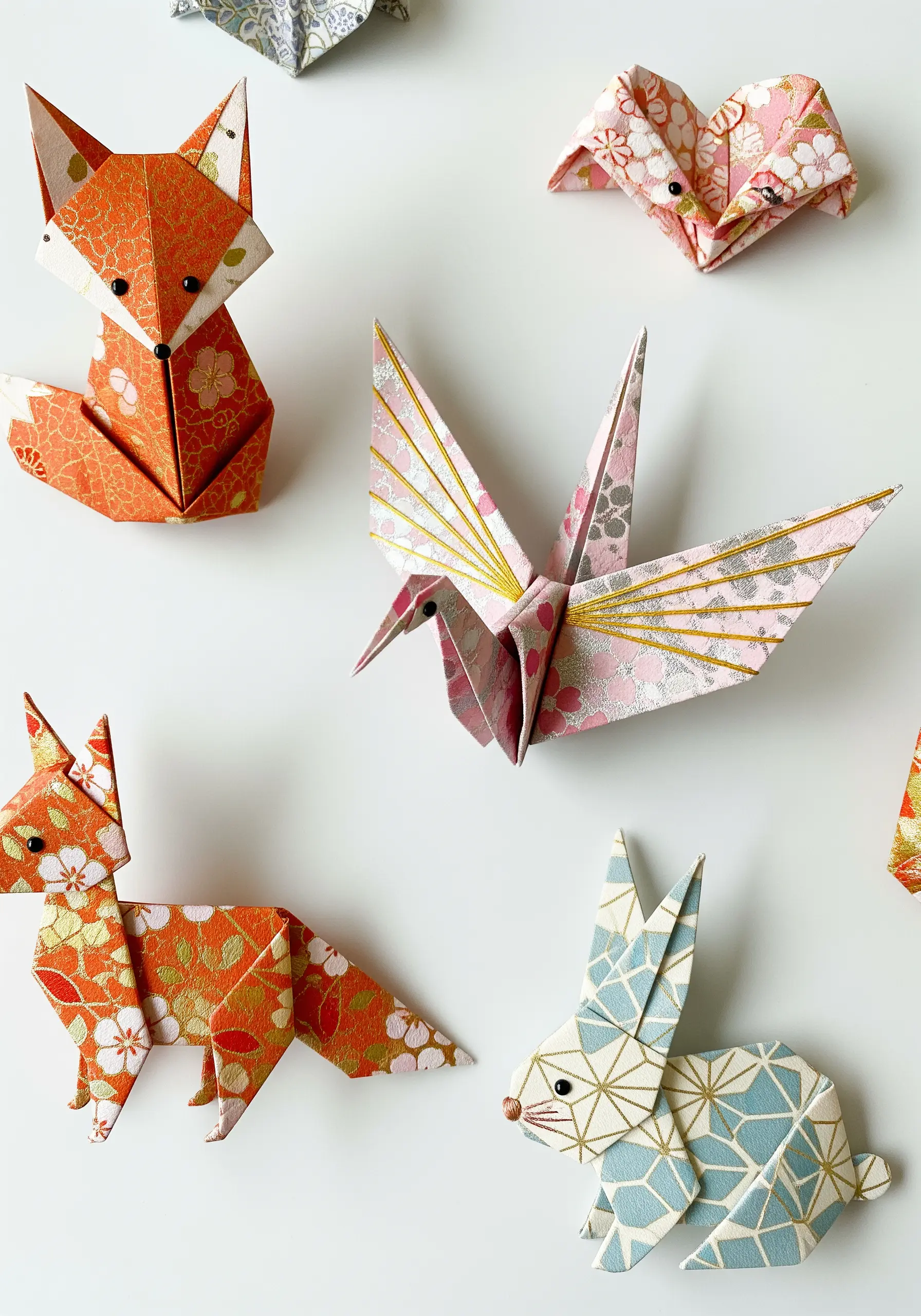 A collection of origami animals made from patterned paper with delicate stitch details.