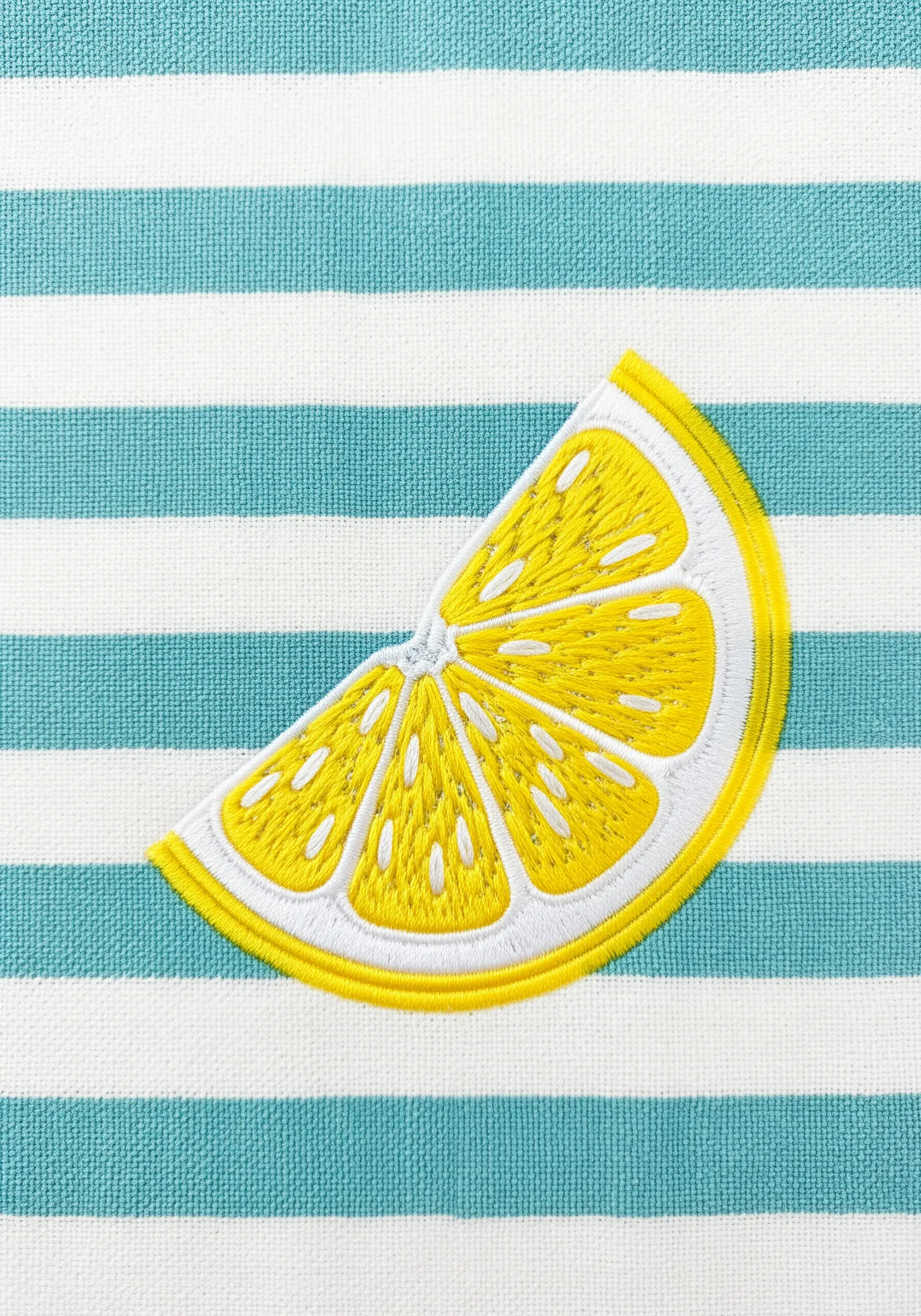 A bright yellow lemon slice embroidered on a turquoise and white striped fabric.
