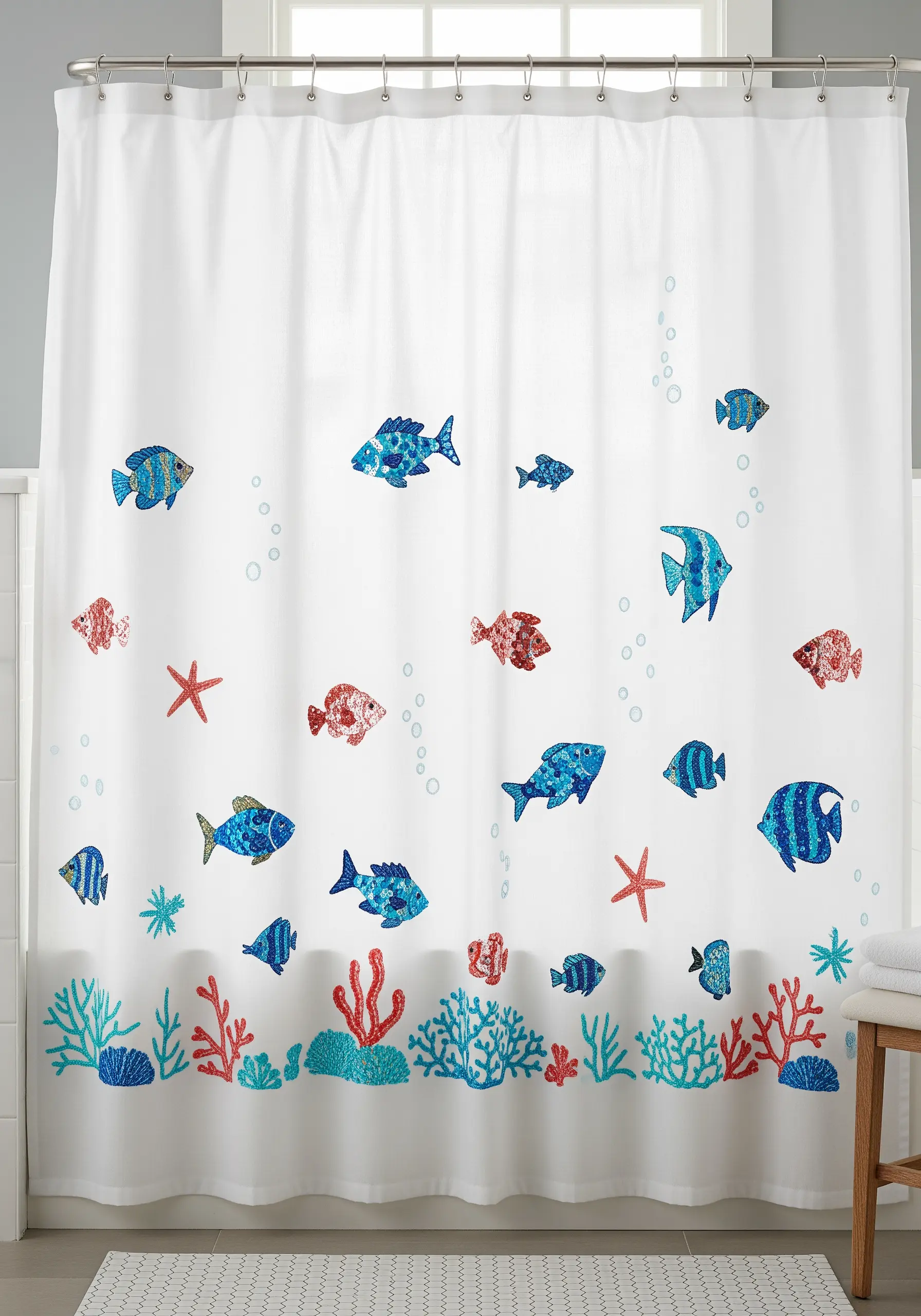 A white shower curtain decorated with blue and red sequined fish and embroidered coral.