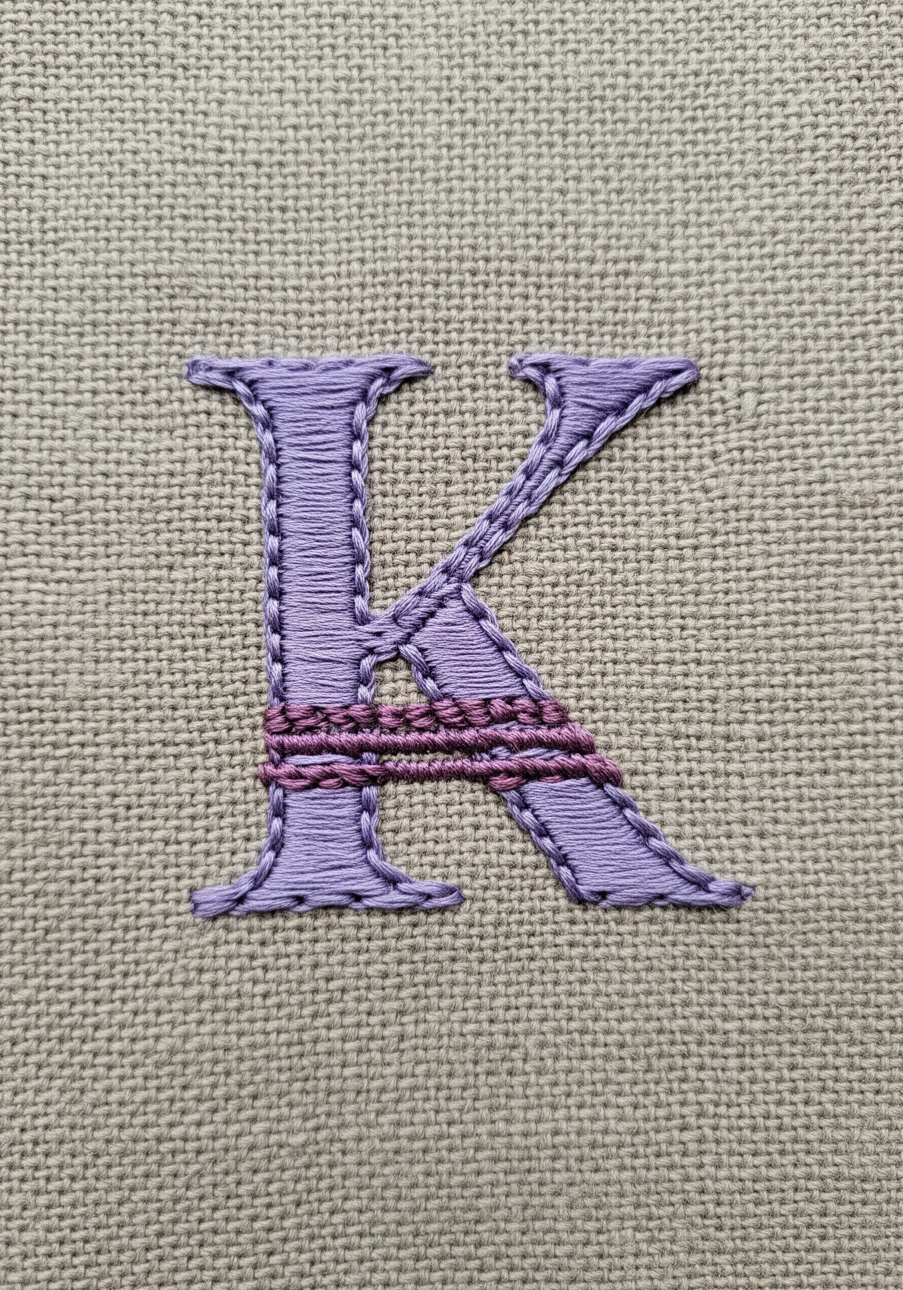 A lavender letter 'K' with a darker purple wrapped detail across the middle.