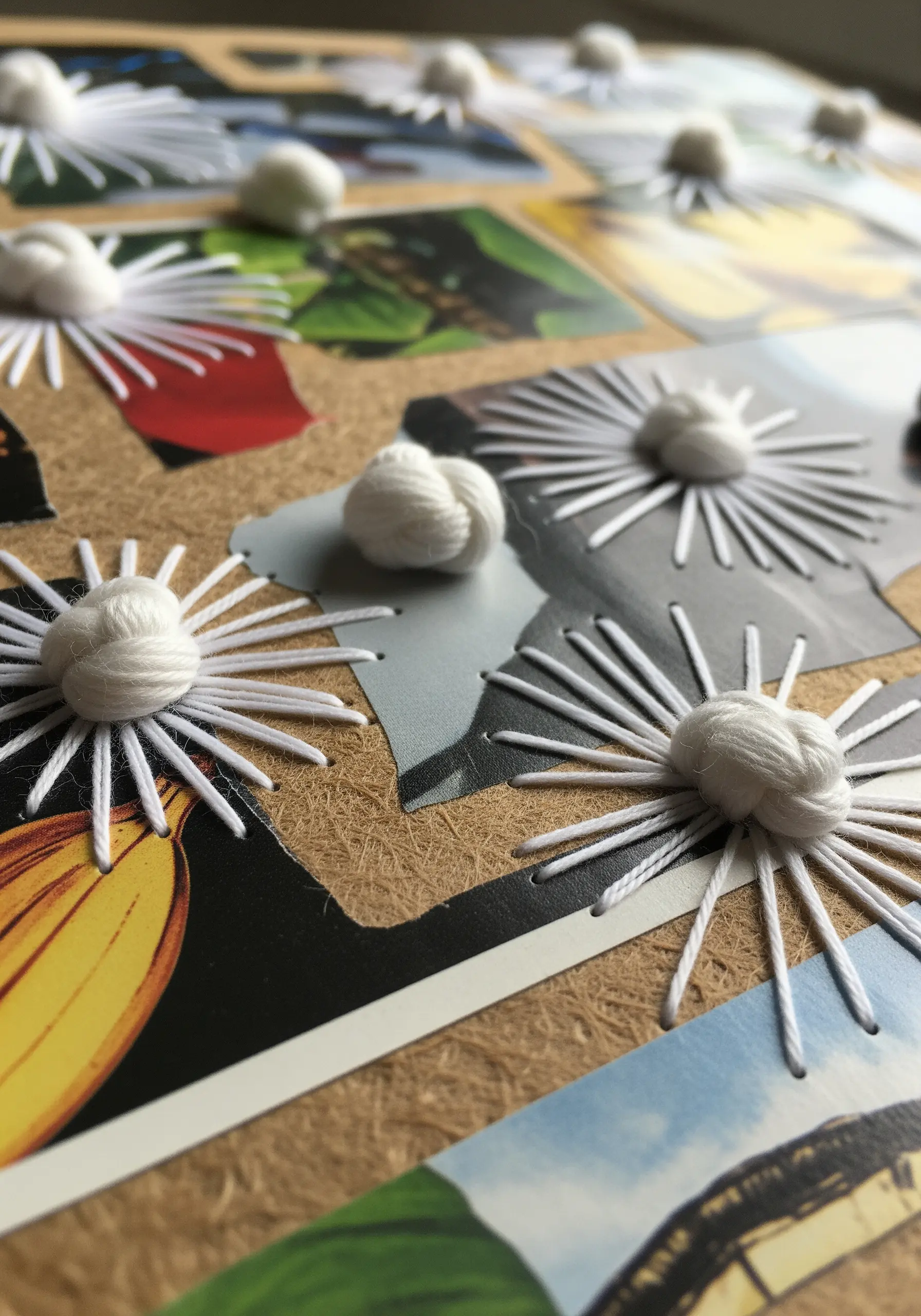 A photo collage on a corkboard with radiating white stitches topped by large, soft yarn knots.
