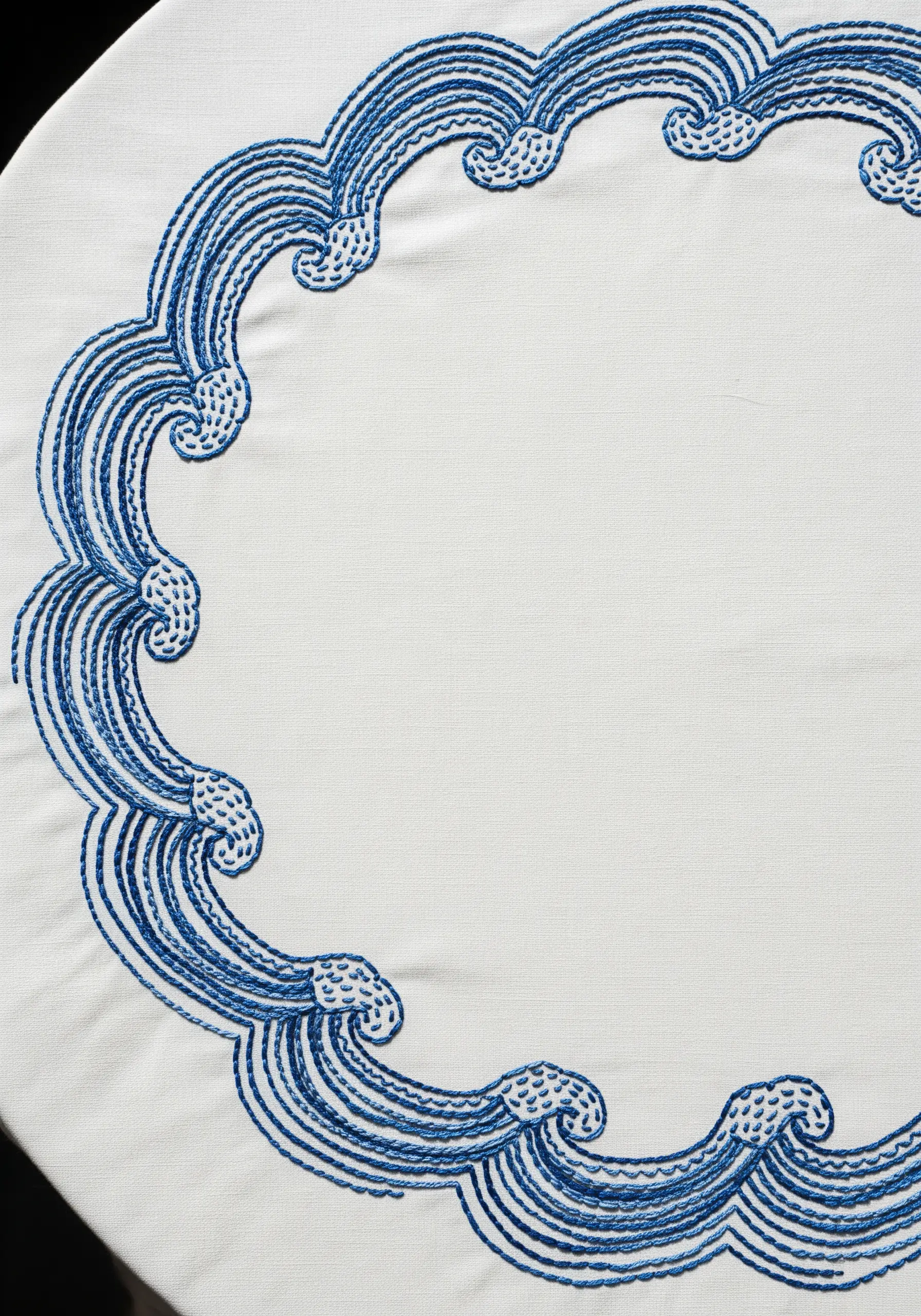 A border of stylized blue waves embroidered on a white tablecloth.