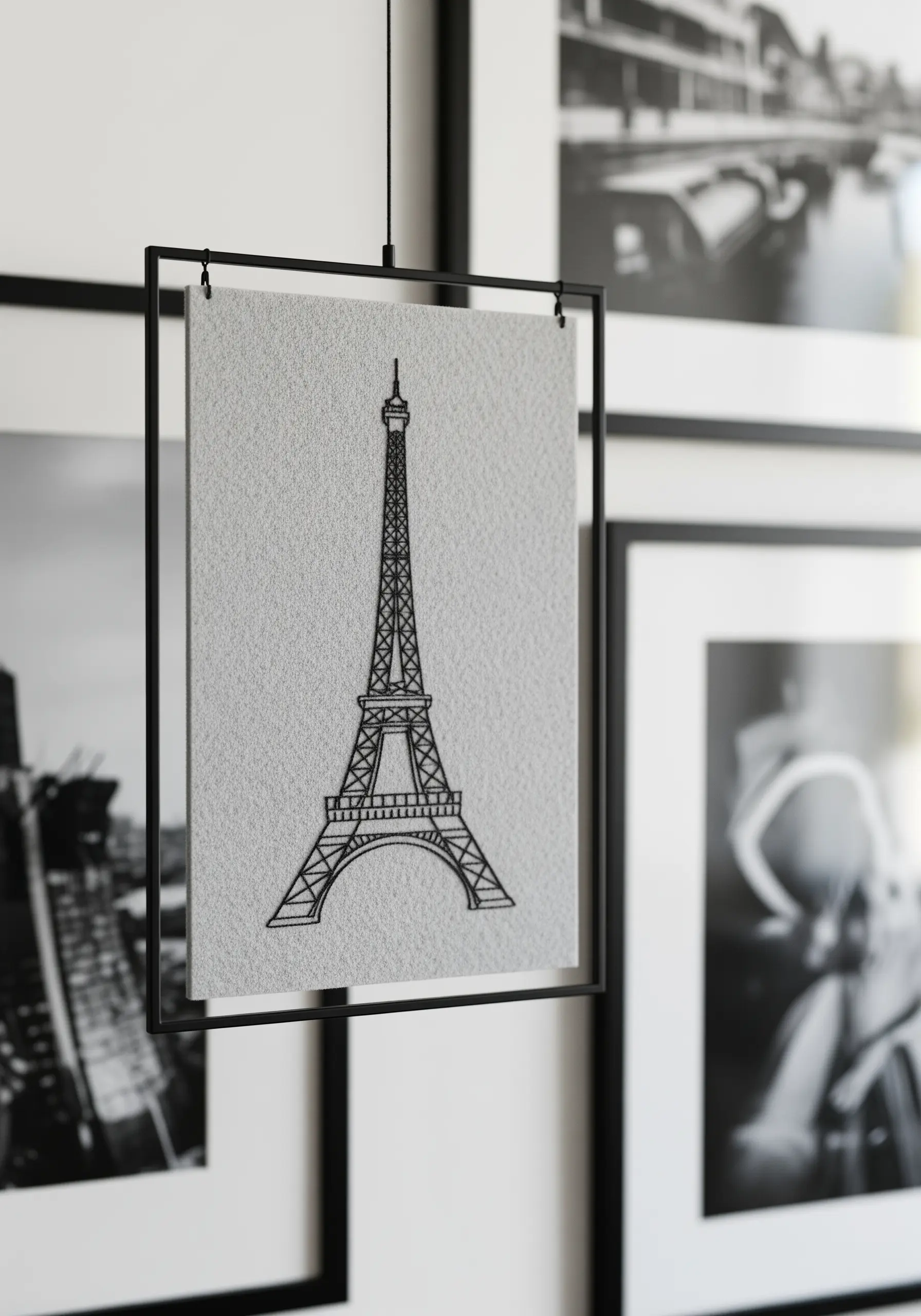 Fine-line black embroidery of the Eiffel Tower in a floating frame.