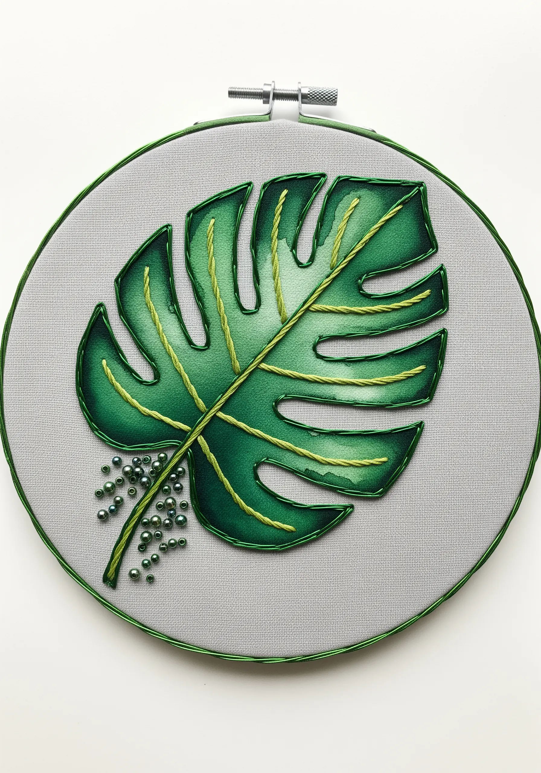 Painted monstera leaf with yellow thread veins and green seed bead embellishments.
