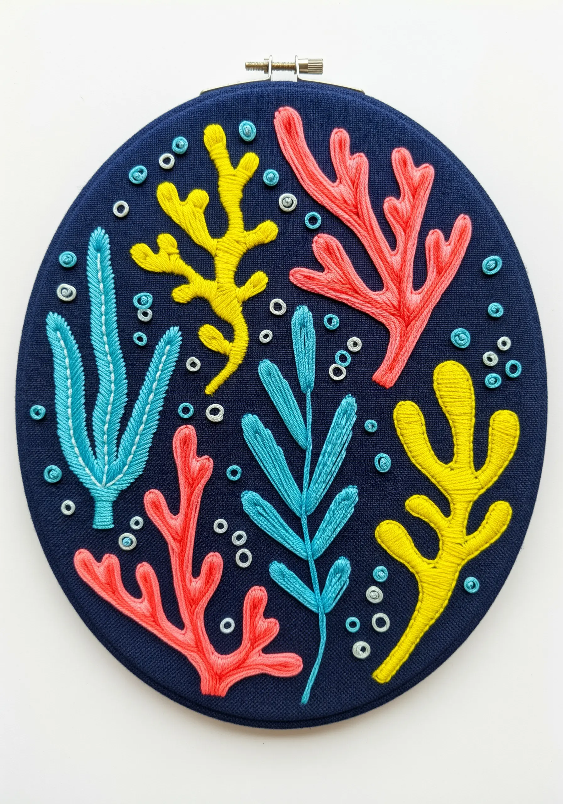 Colorful abstract coral and seaweed embroidered in yellow, pink, and blue on navy fabric.