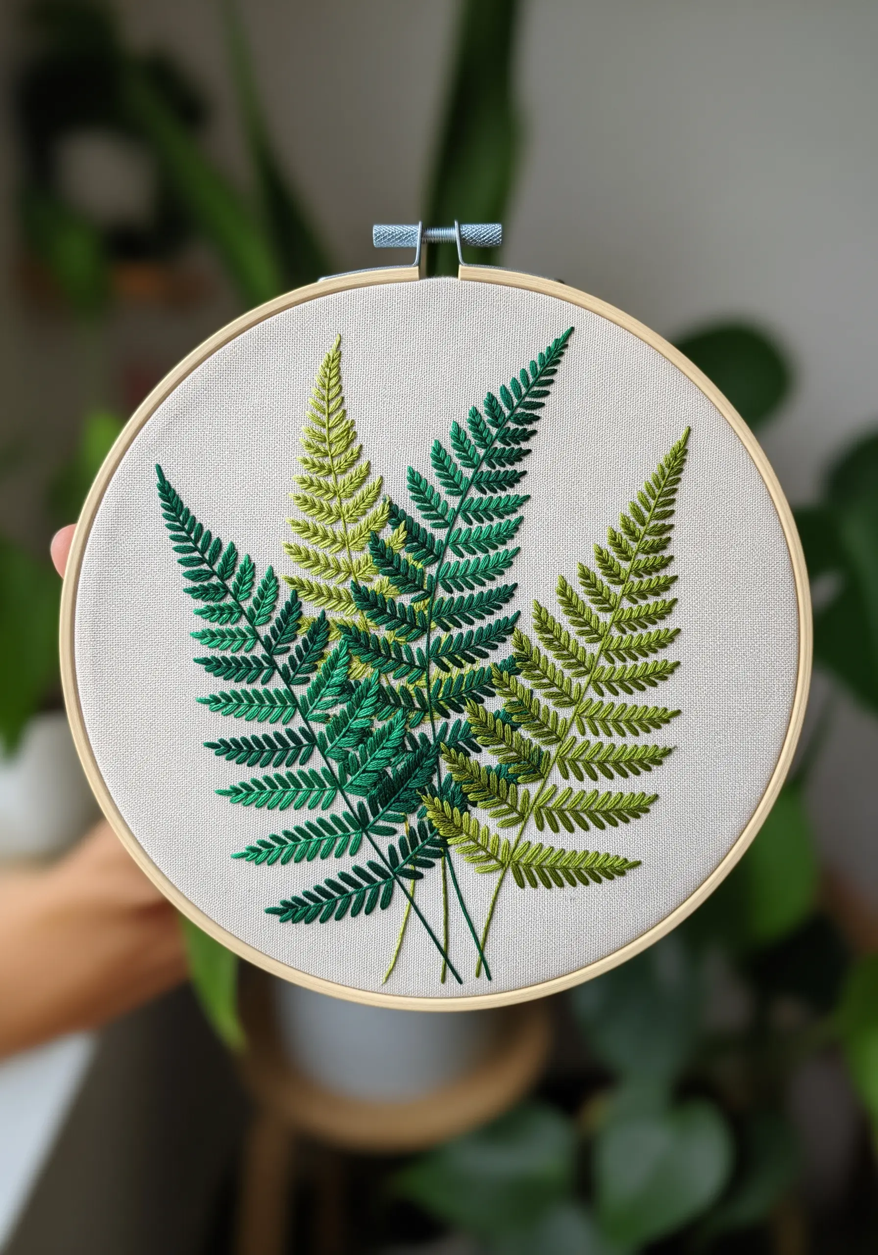 Three embroidered ferns in varying shades of green, creating a sense of depth.