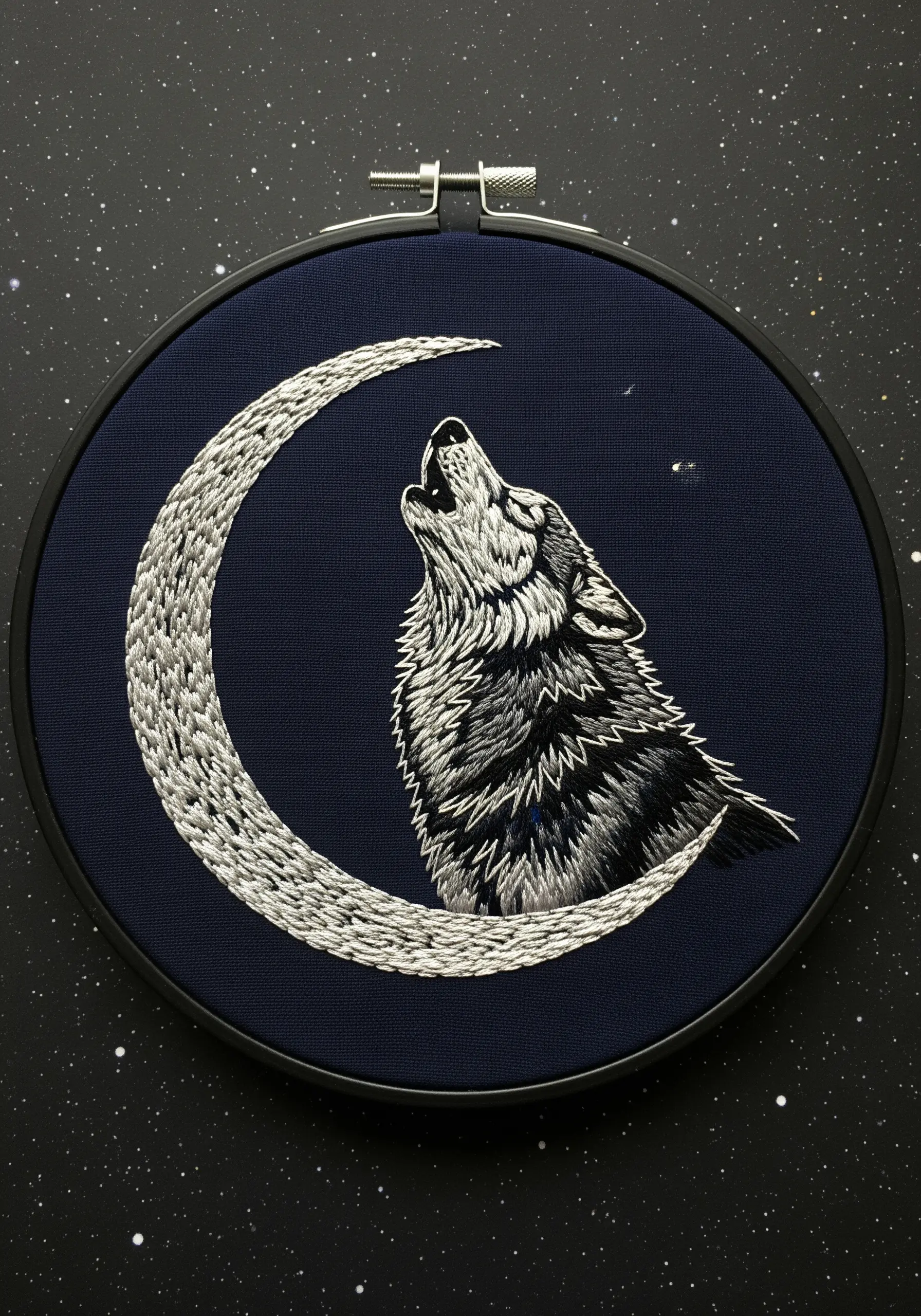 A howling wolf embroidered in white and gray against a crescent moon on dark blue fabric.