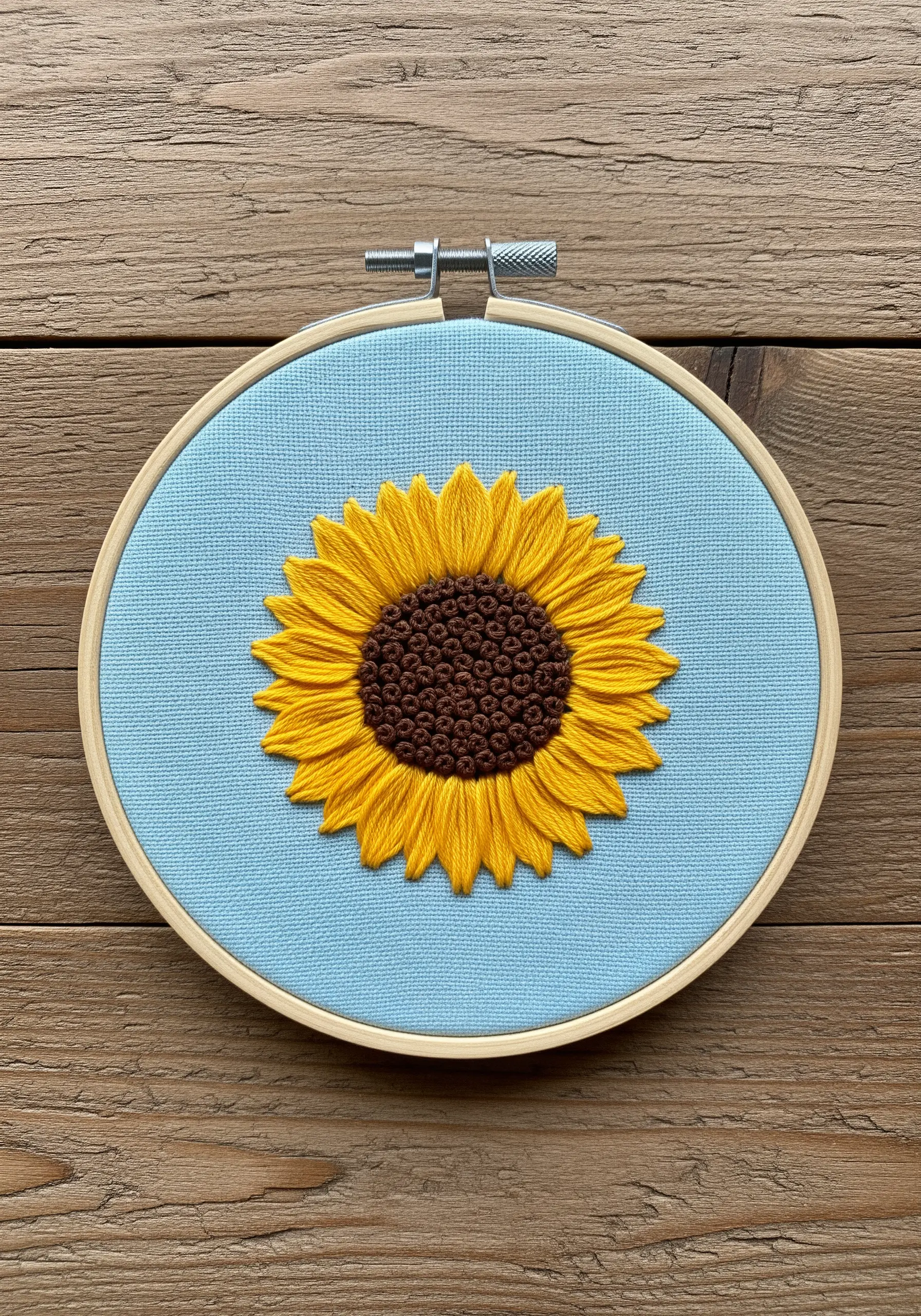 Embroidered sunflower with a dense brown French knot center and yellow fishbone stitch petals.