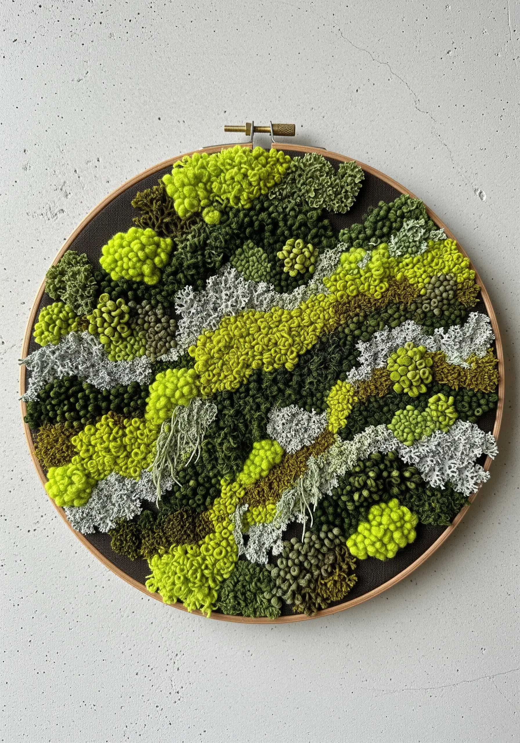 A textural embroidery hoop filled with green and white French knots and bullion knots simulating moss.