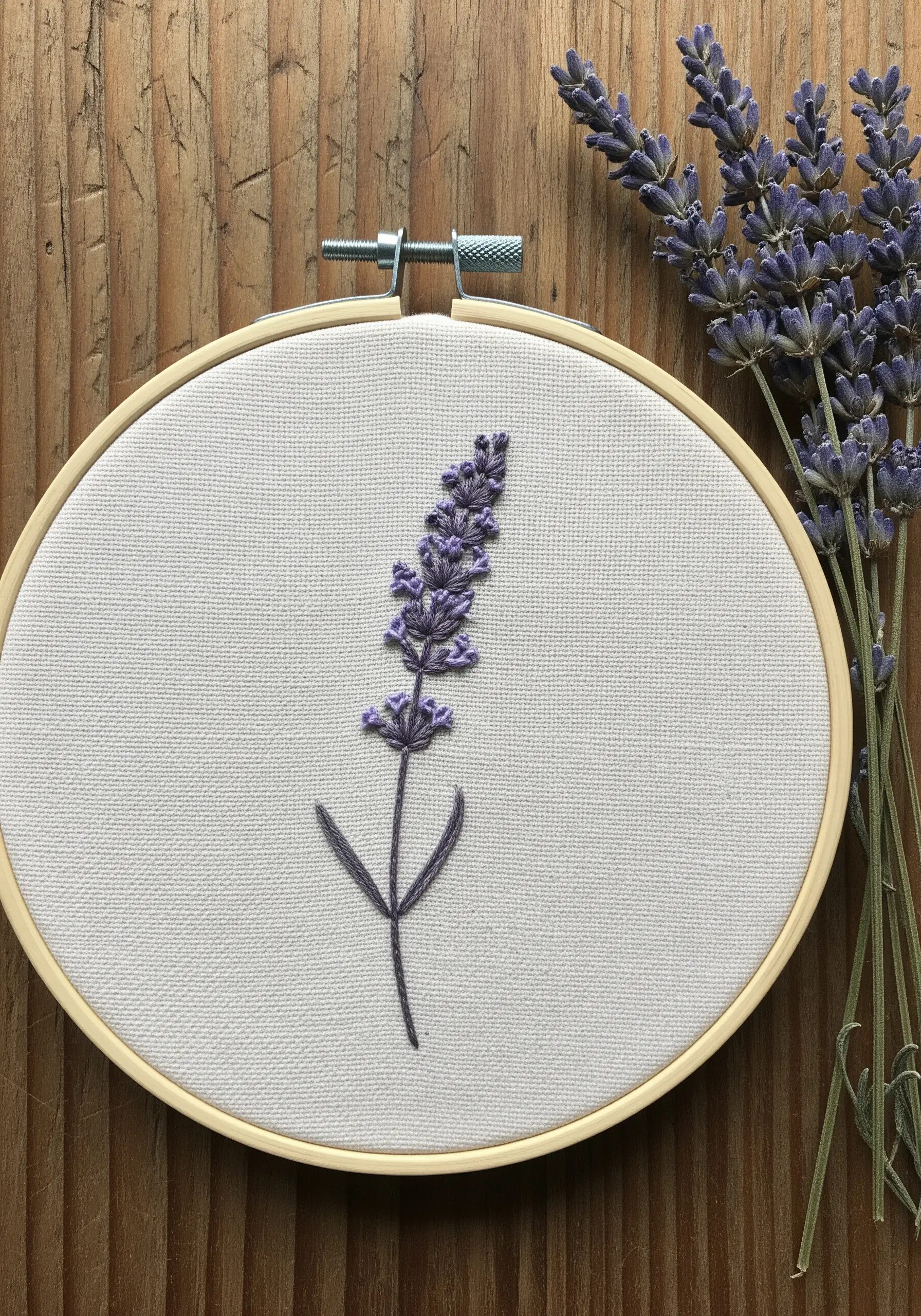 A simple lavender sprig embroidered in purple and grey-green thread on off-white linen.