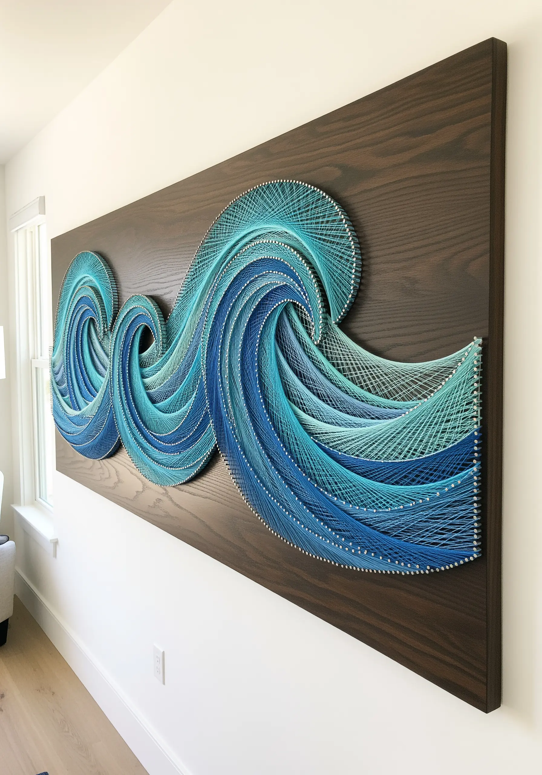 Large, multi-panel string art of swirling ocean waves in shades of blue and turquoise