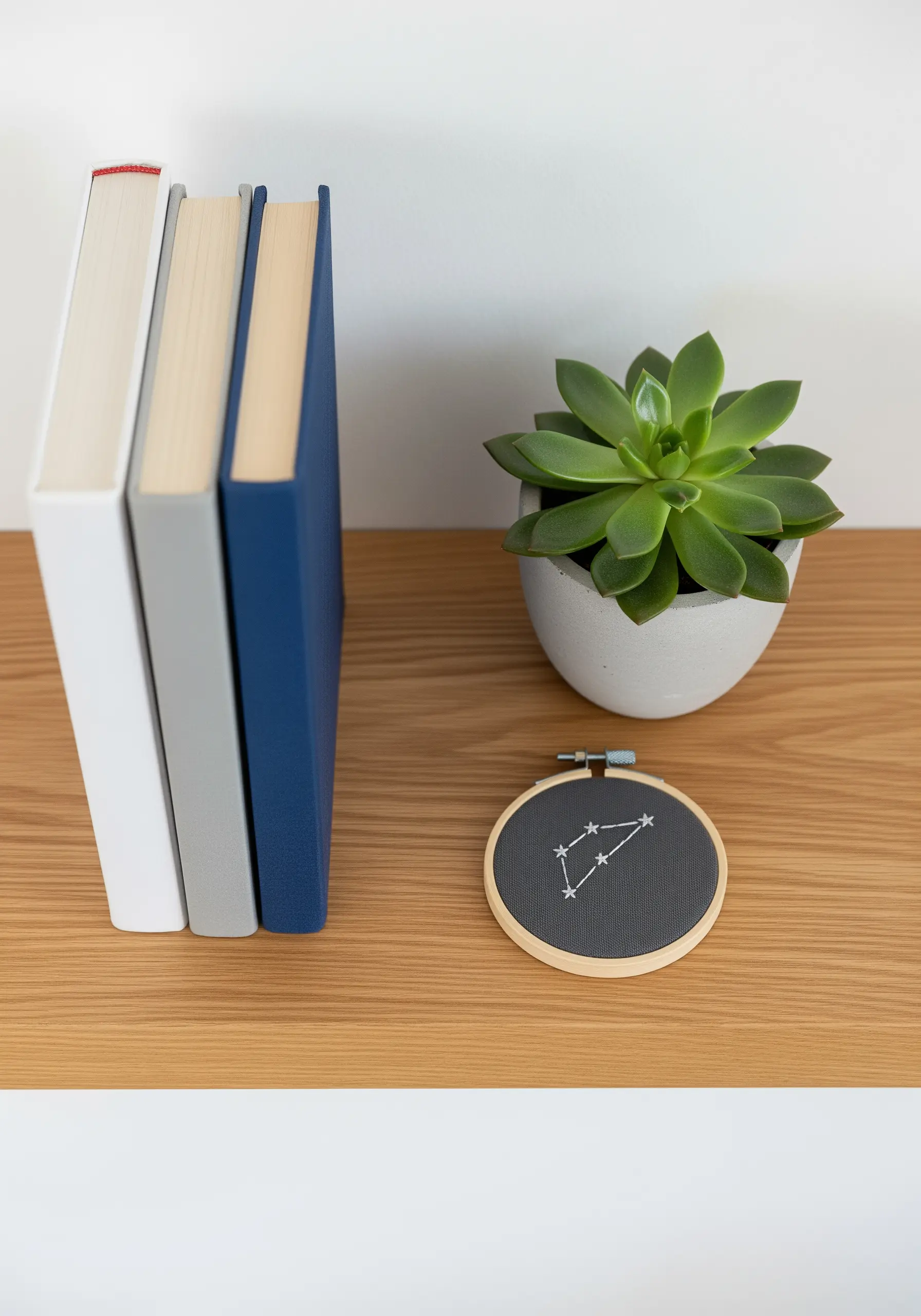 A small embroidery hoop with a white constellation stitched on dark gray fabric