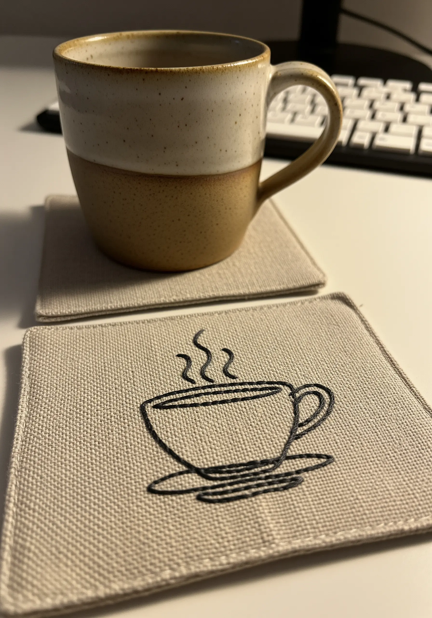 A line art coffee cup embroidered in a sketchy style on a linen coaster