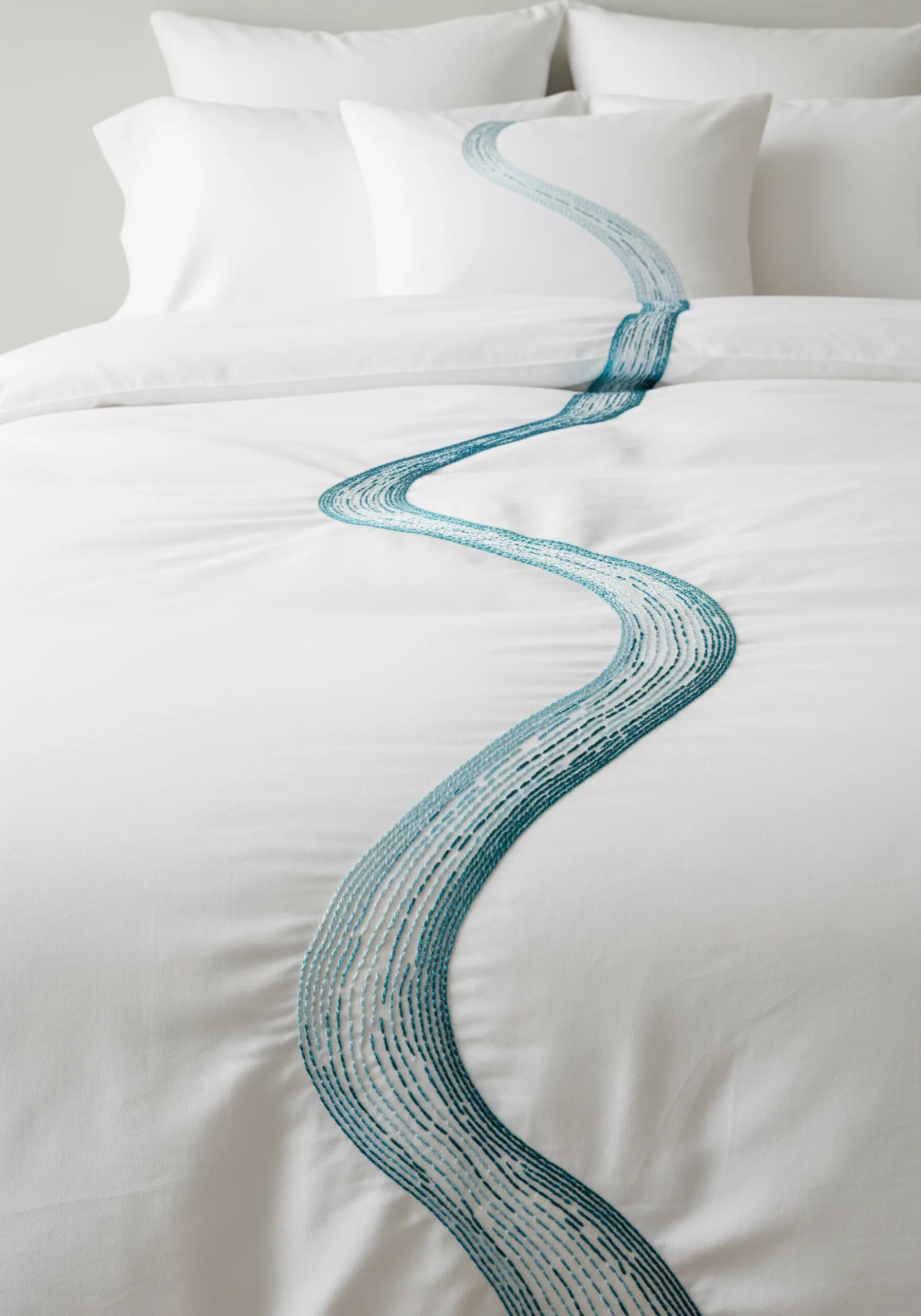 A white duvet cover with a long, winding river motif embroidered in shades of teal.