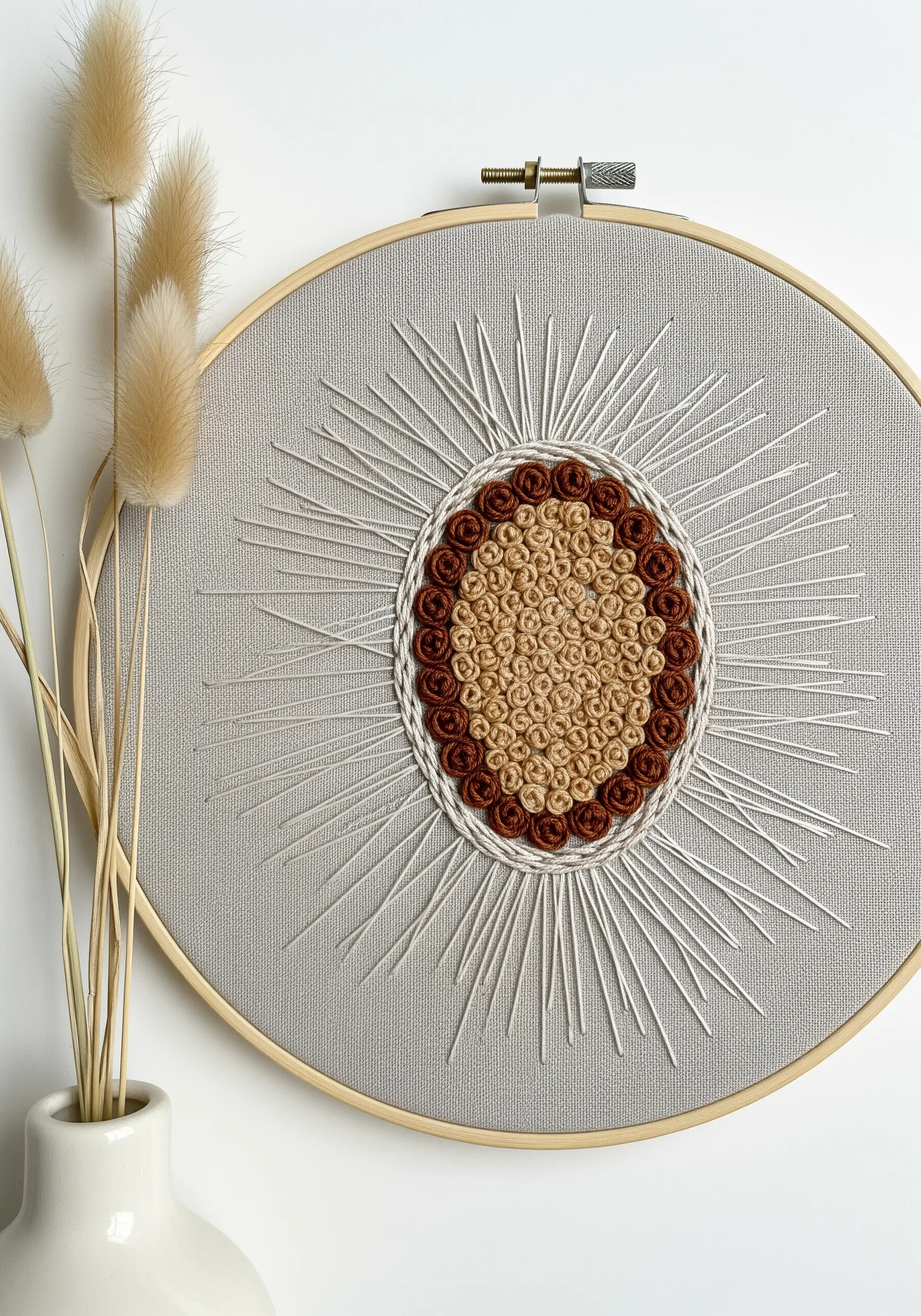 Hoop art with a central medallion of brown and tan bullion knots and radiating white stitches.
