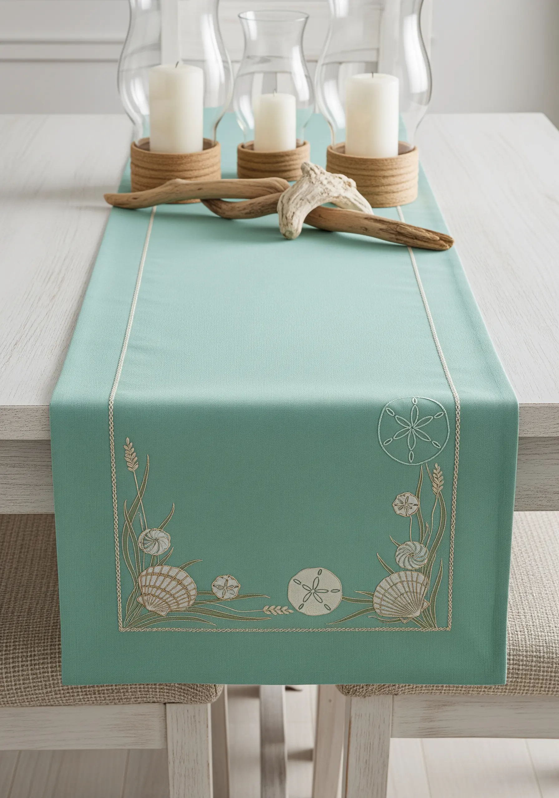 Two-tone embroidery of seashells and sea grass in beige and white on a seafoam green runner.