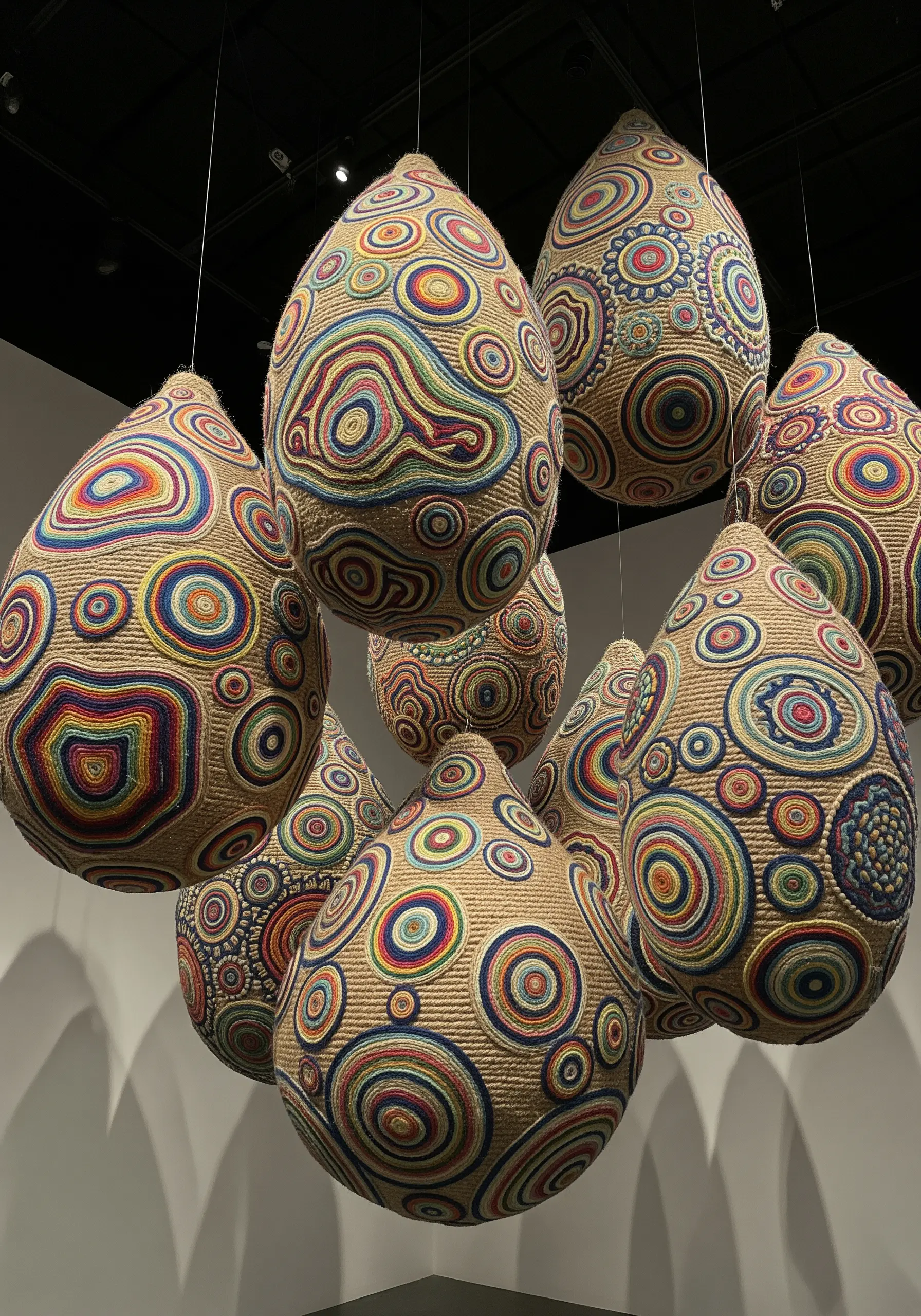 Large teardrop-shaped sculptures wrapped in concentric circles of colorful yarn.