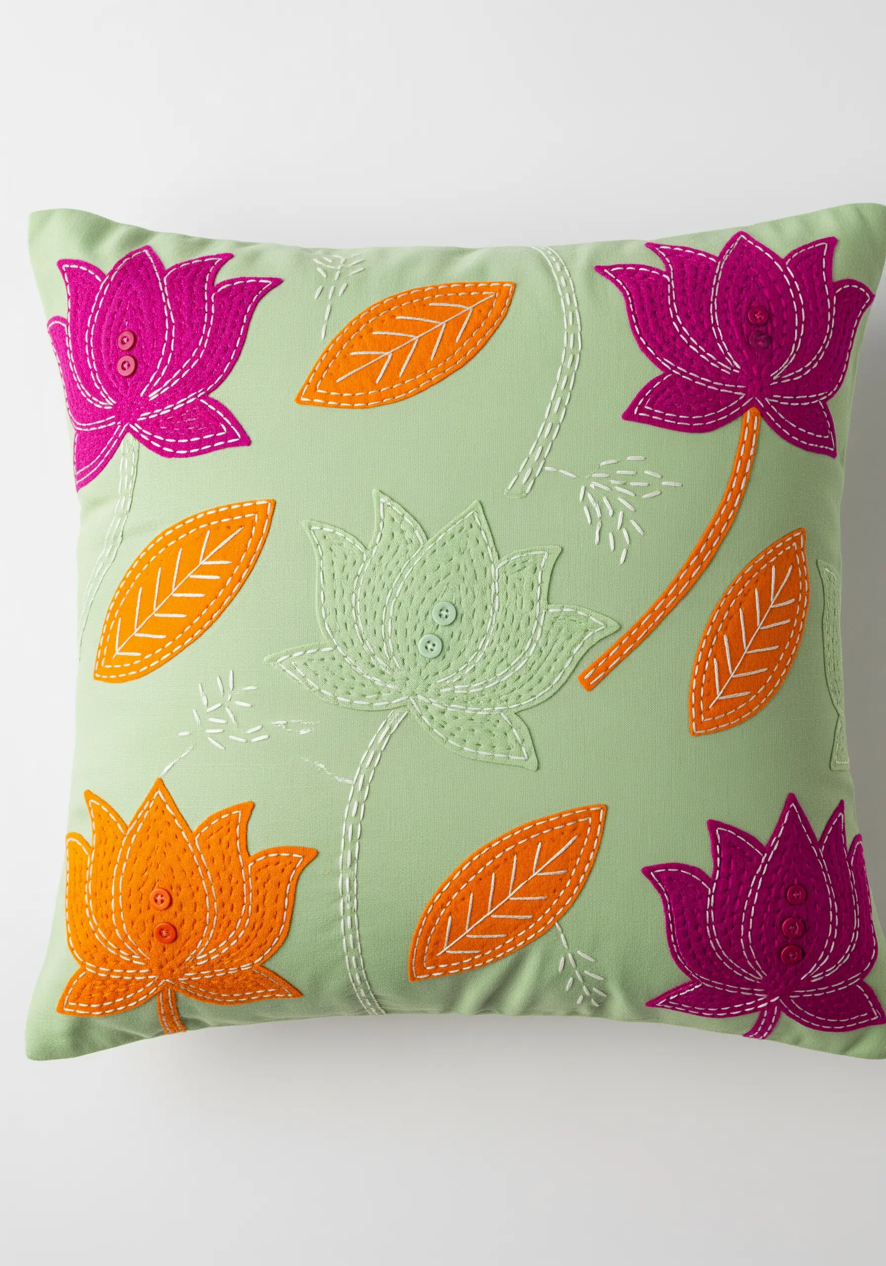 Appliqué flowers and leaves secured with visible running stitch on a green cushion