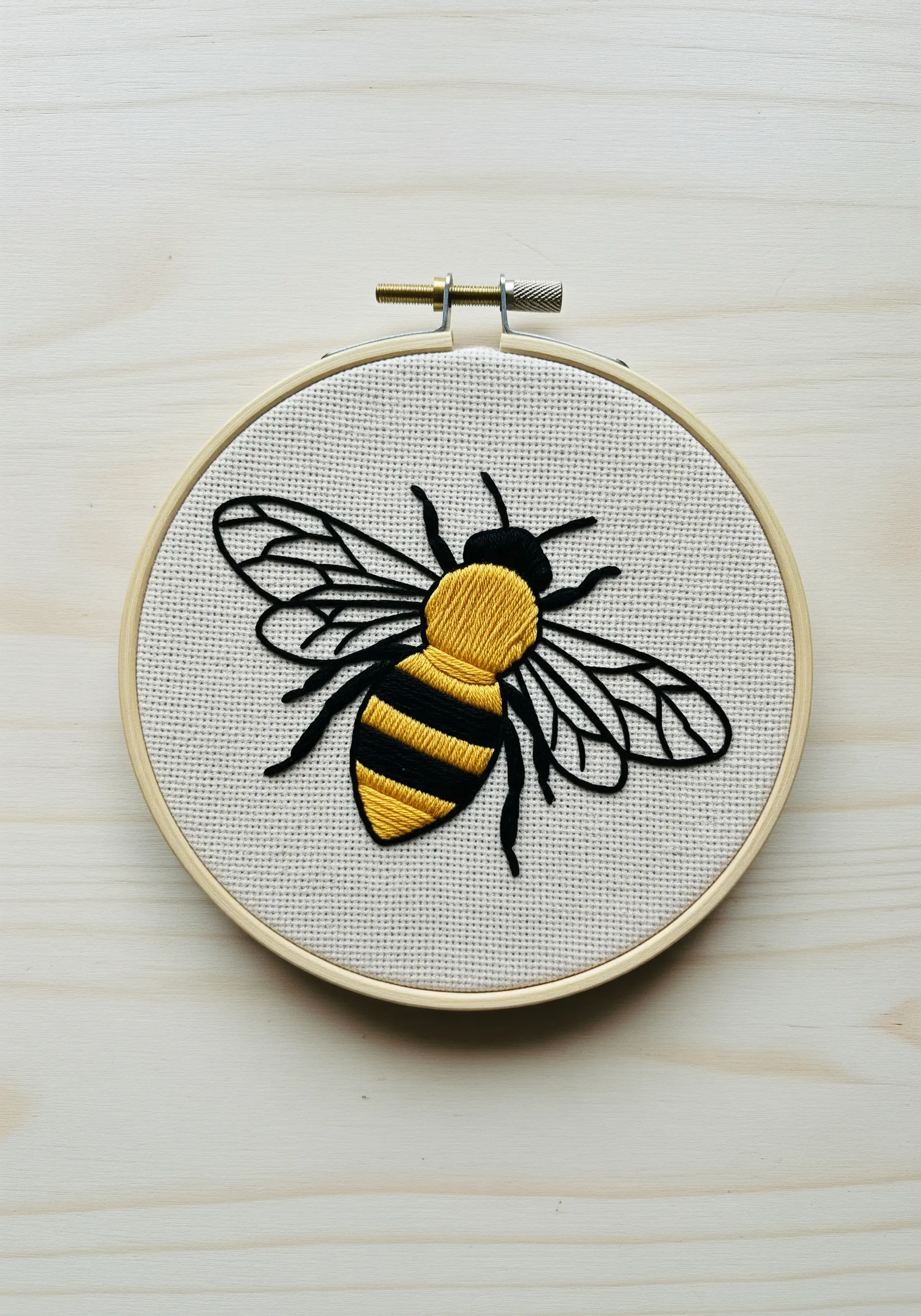 A honeybee with satin-stitched yellow and black stripes and fine black line work for wings.