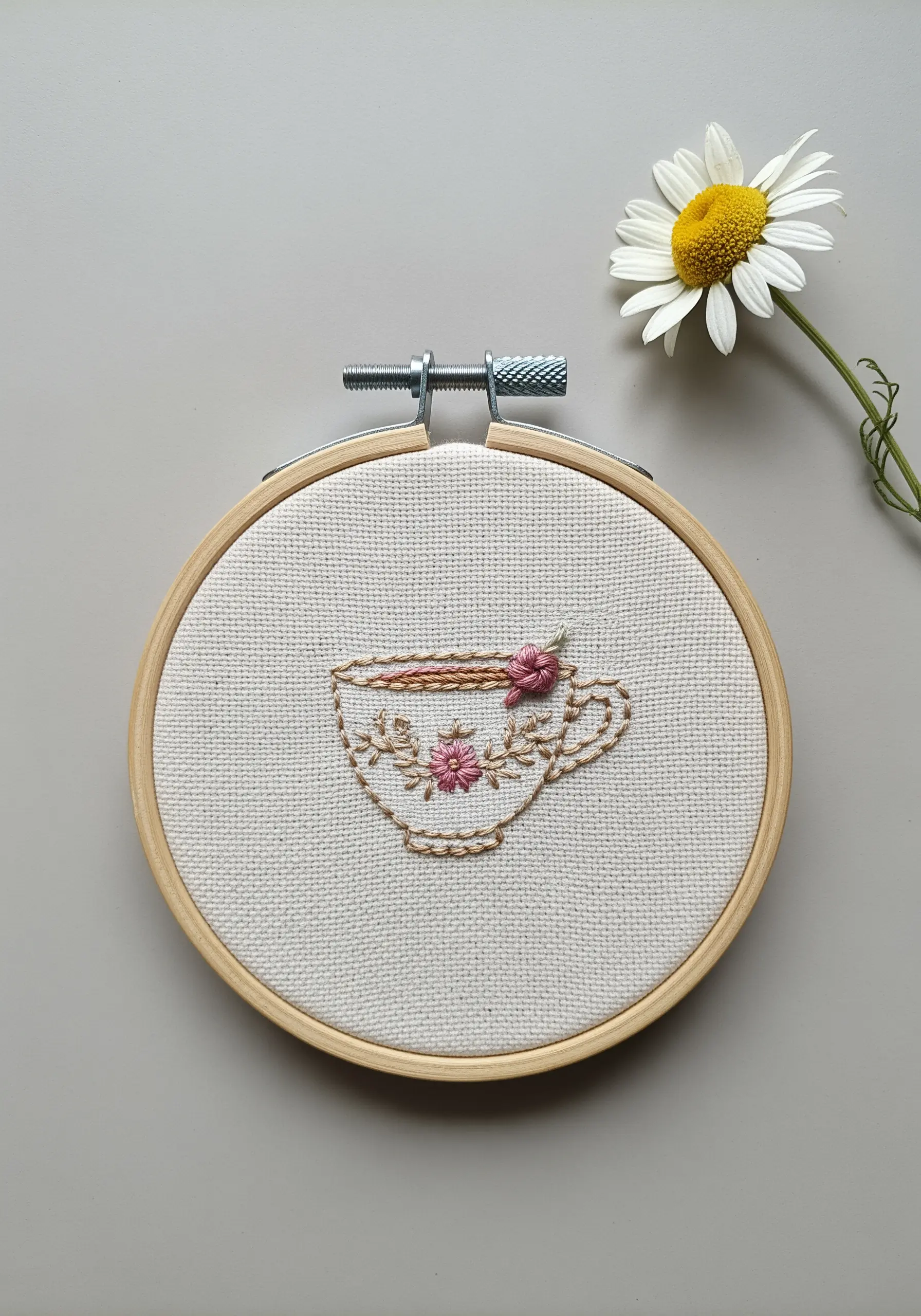 Embroidered teacup outline with a pink woven wheel rose detail.