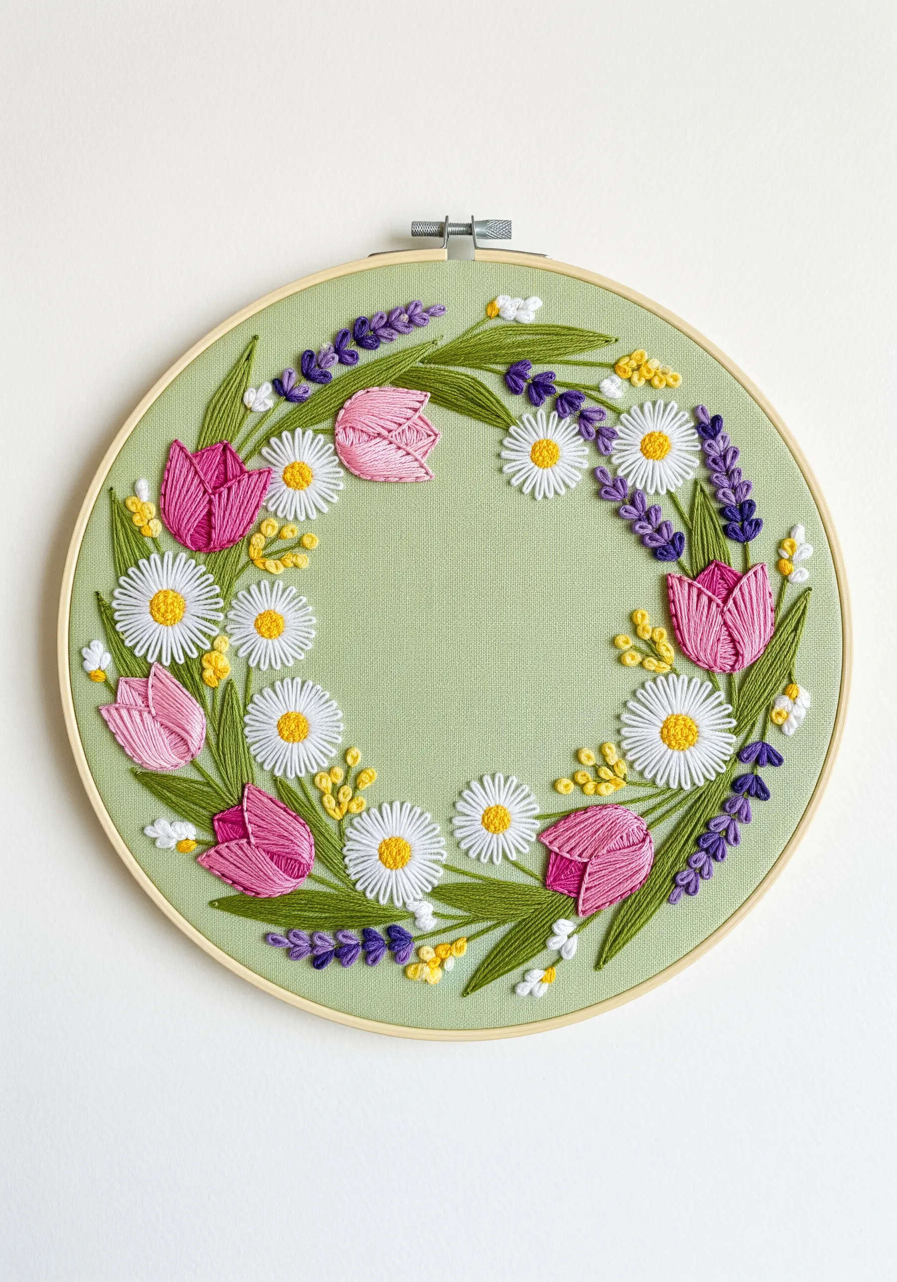 Embroidered spring floral wreath with tulips, daisies, and lavender on green fabric.