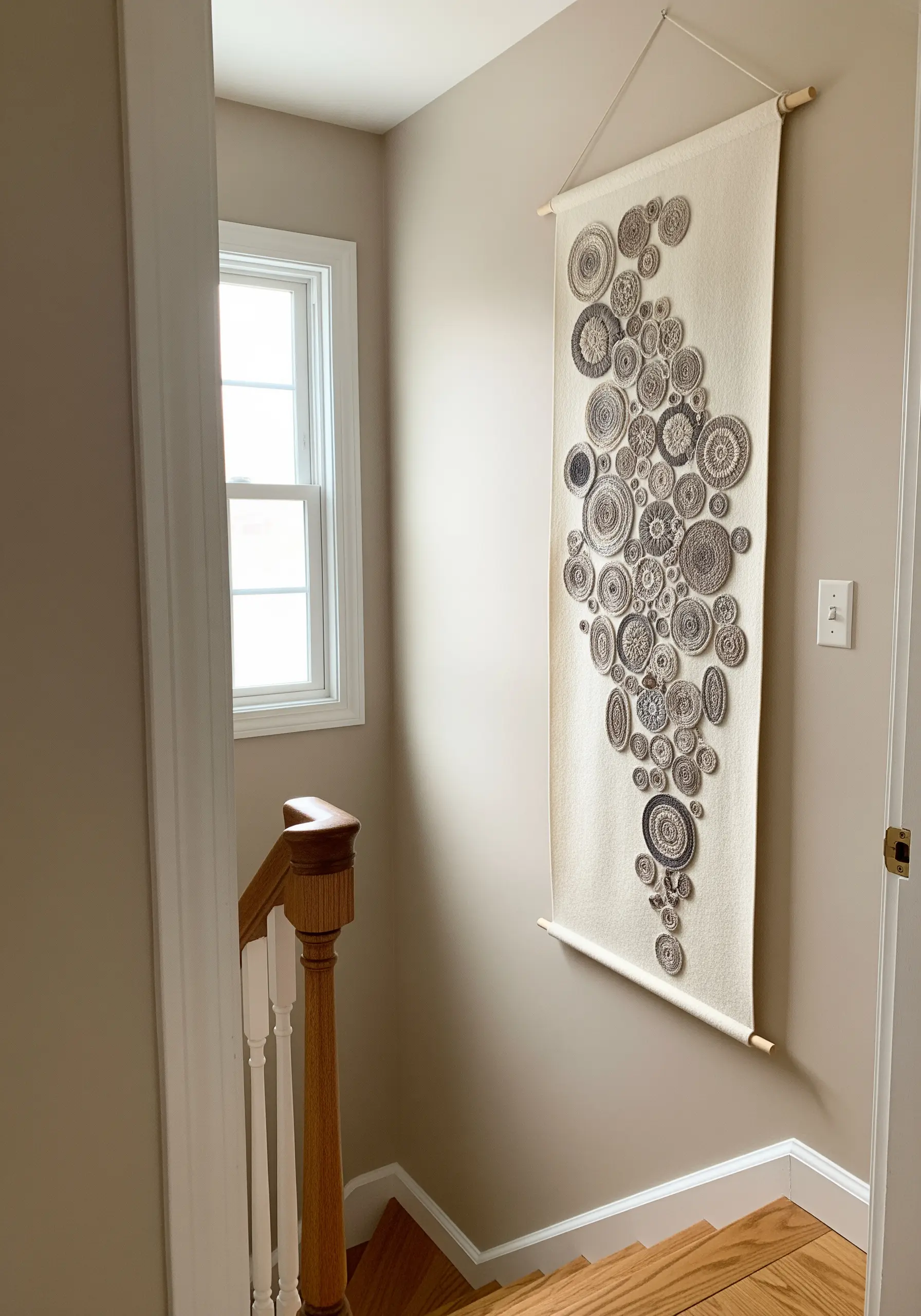 A long wall hanging decorated with a cascade of small, circular embroidered appliqué motifs.