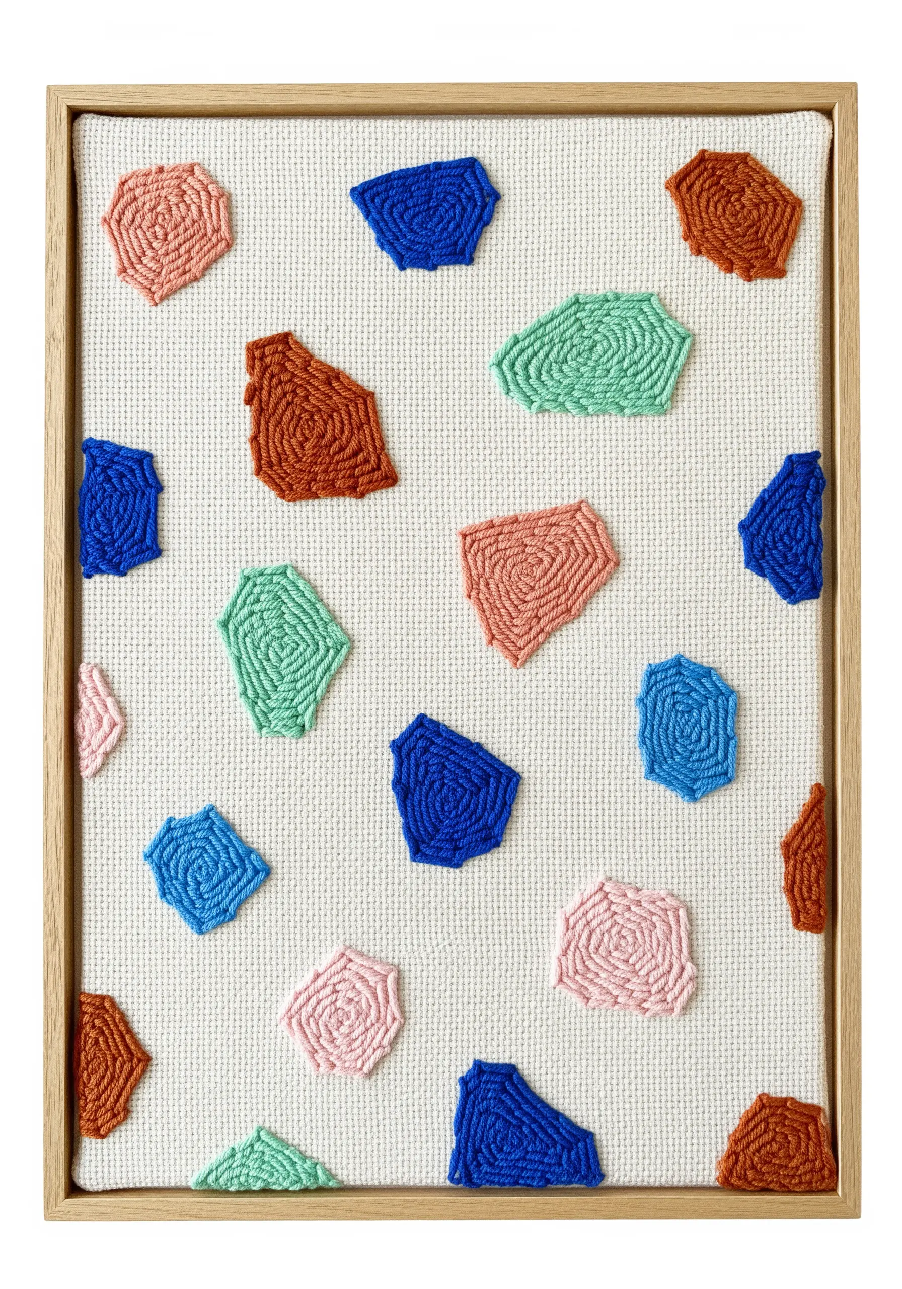 Framed artwork featuring small, colorful, organically shaped punch needle pieces on a white canvas.