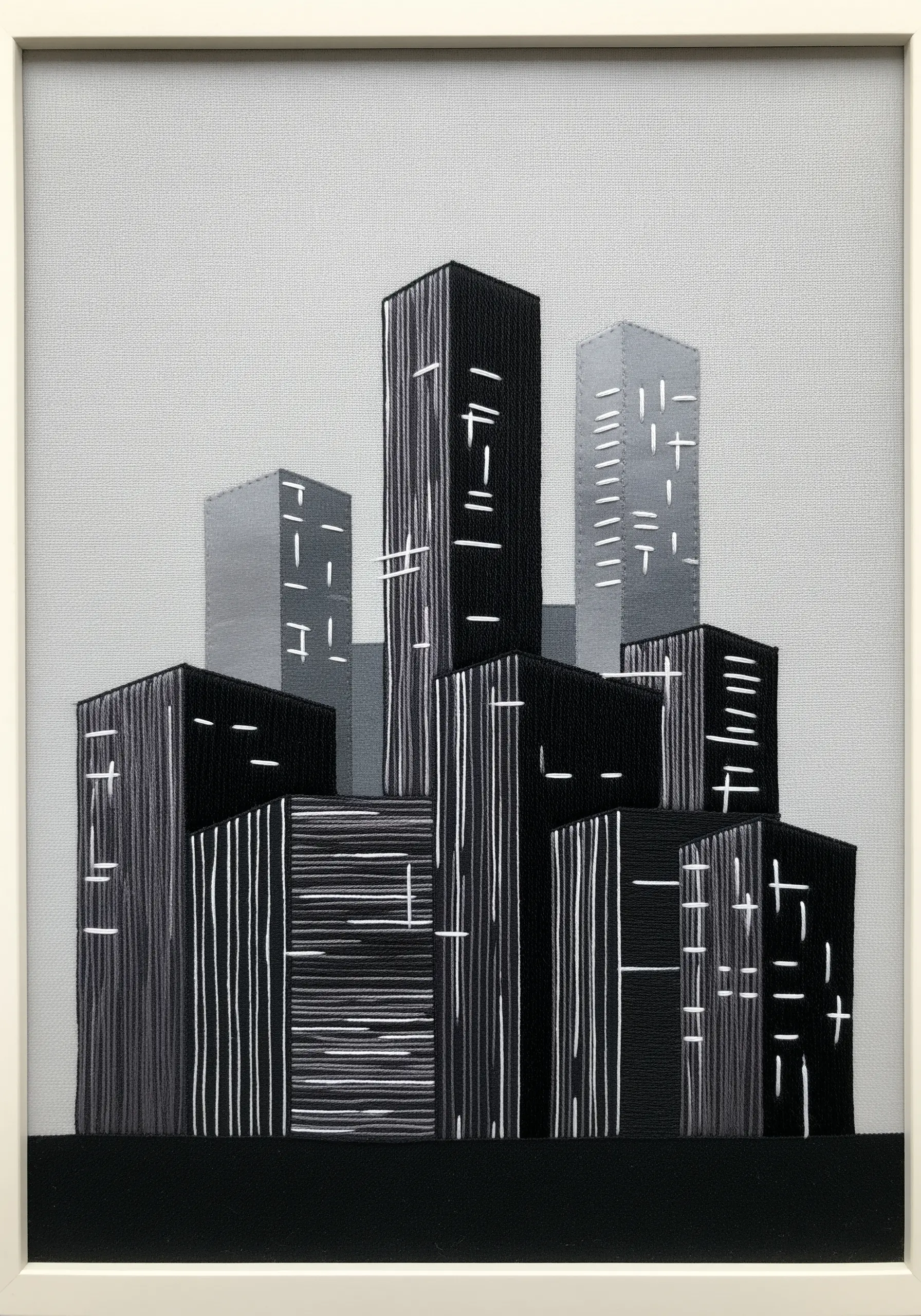An embroidered cityscape using vertical satin stitches in black and gray, with white accent stitches.