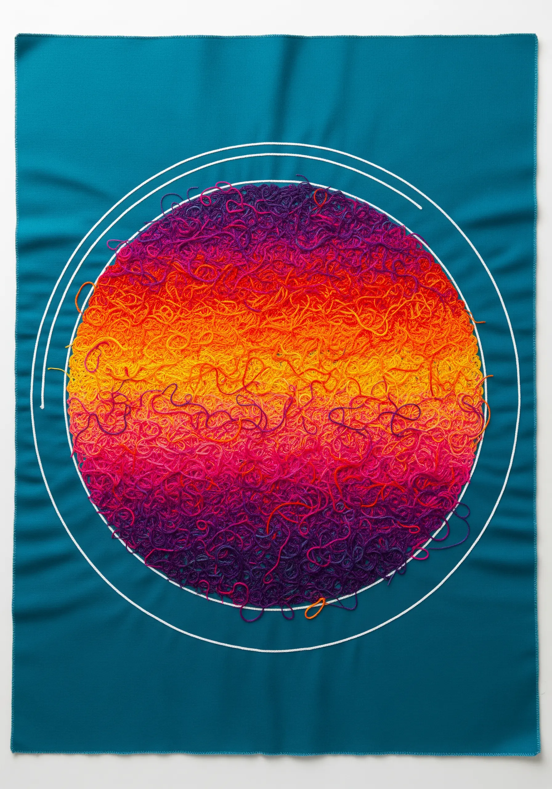 A circle filled with dense, chaotic, textural embroidery in a warm-to-cool gradient.