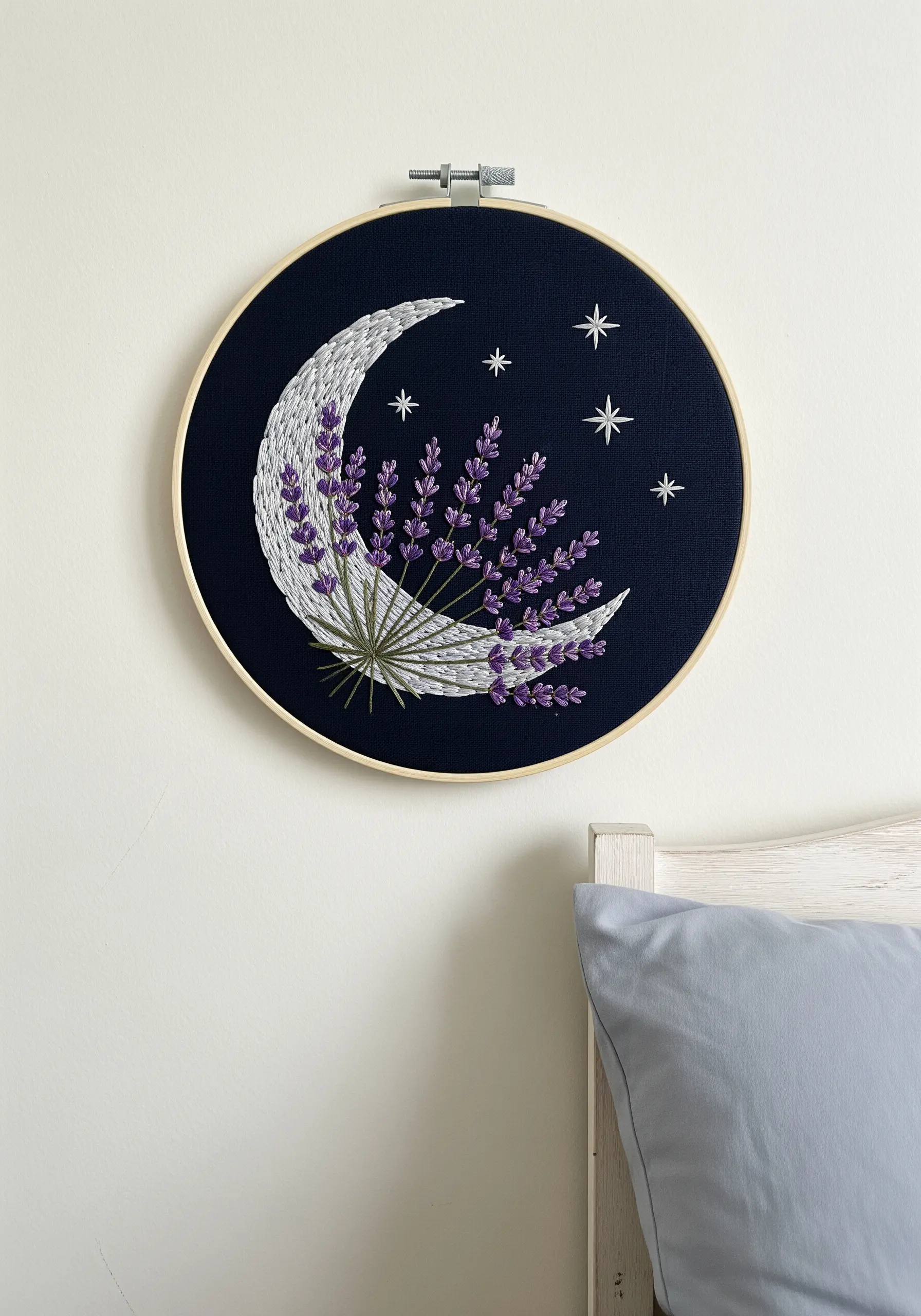 A crescent moon filled with a lavender bouquet, embroidered on dark navy fabric.