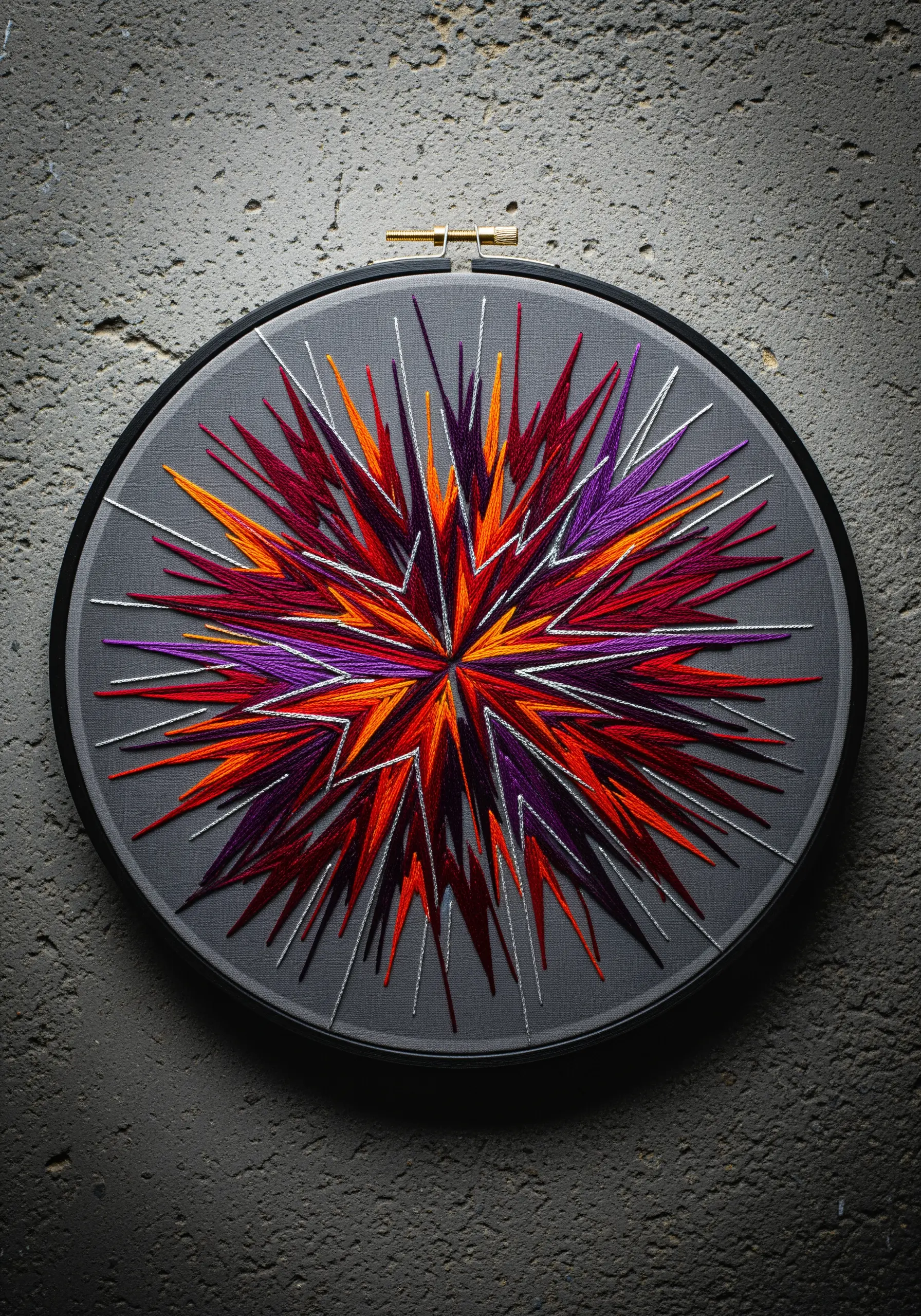 An explosive starburst of red, orange, and purple stitches with silver accents on grey fabric.